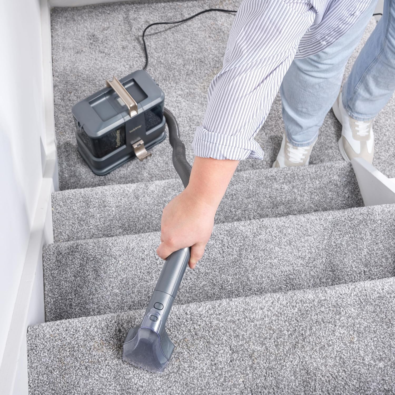 Person cleaning a sofa with the spot cleaner
