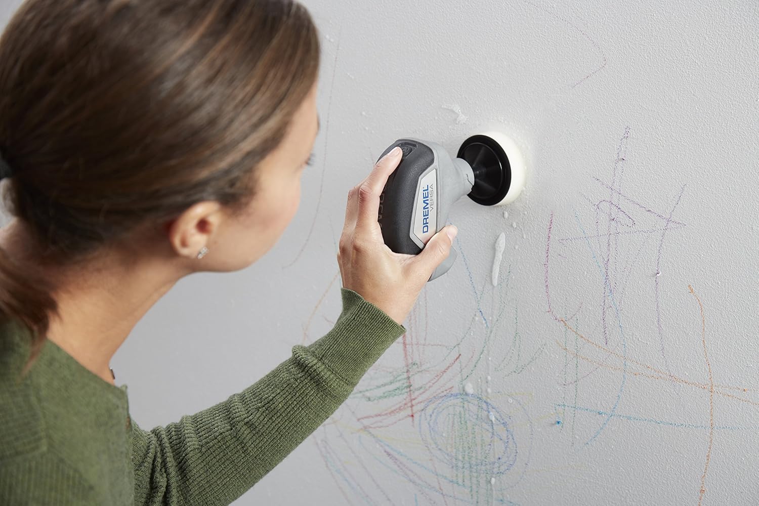 A person using the Dremel Versa tool to clean marks off a wall.