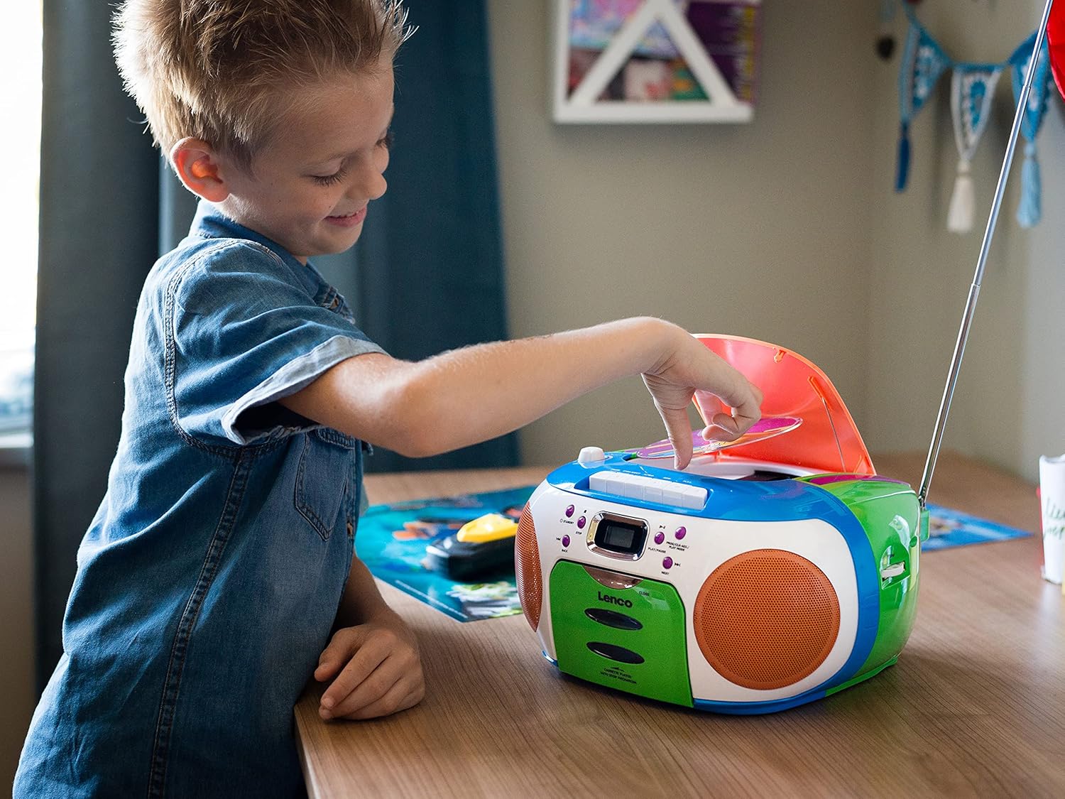 A child's hand opening the CD compartment of the Lenco SCD-971 Boombox.