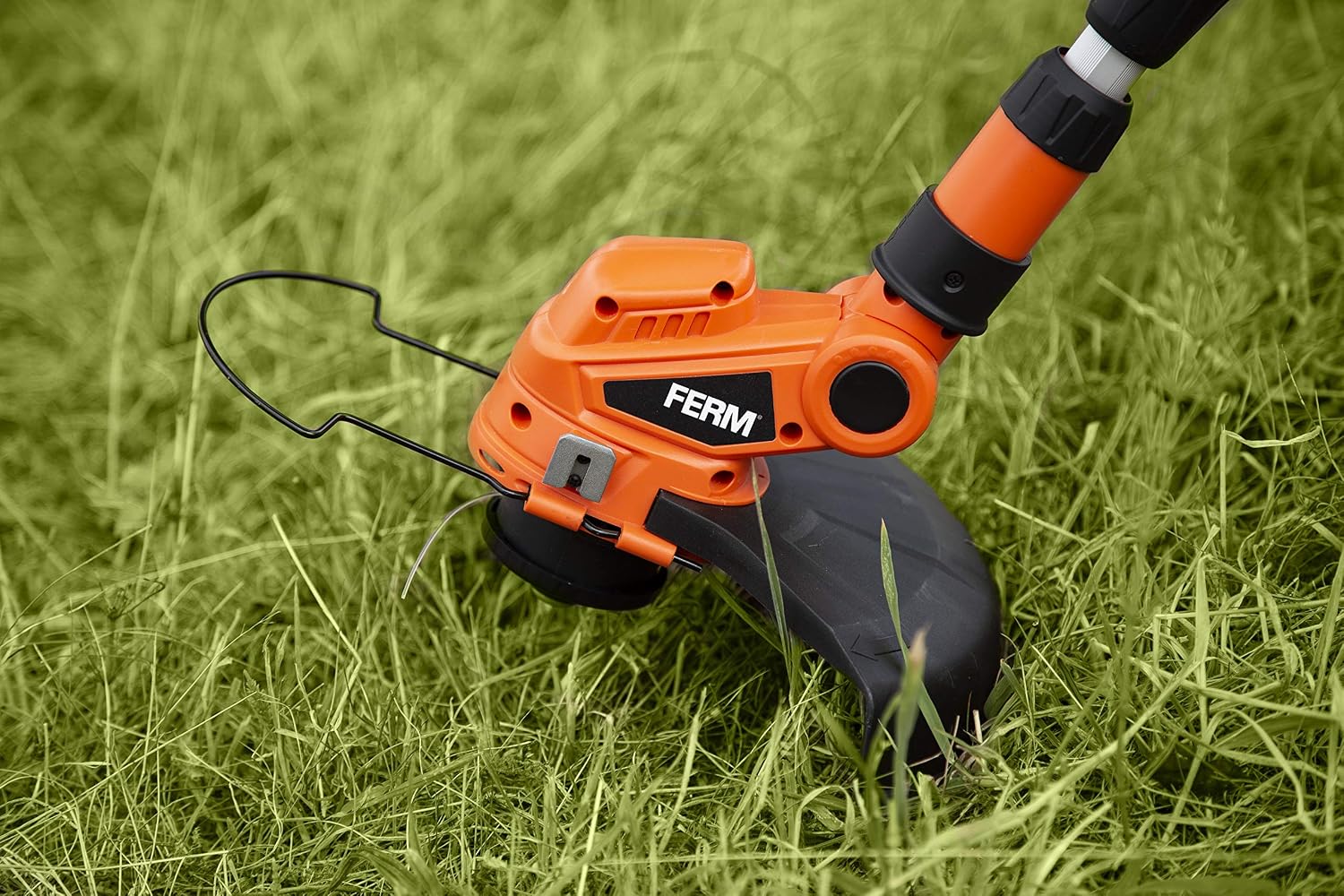 Close-up of the FERM GTM1003 trimmer head actively cutting grass