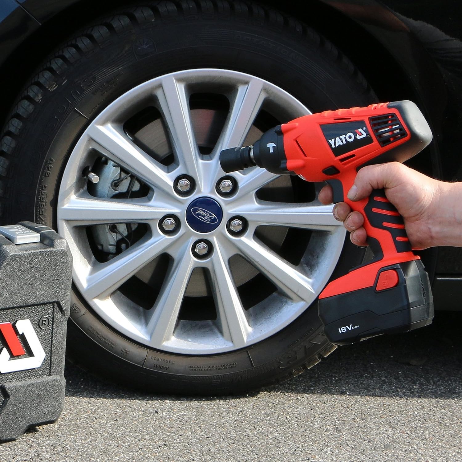 Person using Yato impact wrench to remove a lug nut from a car wheel