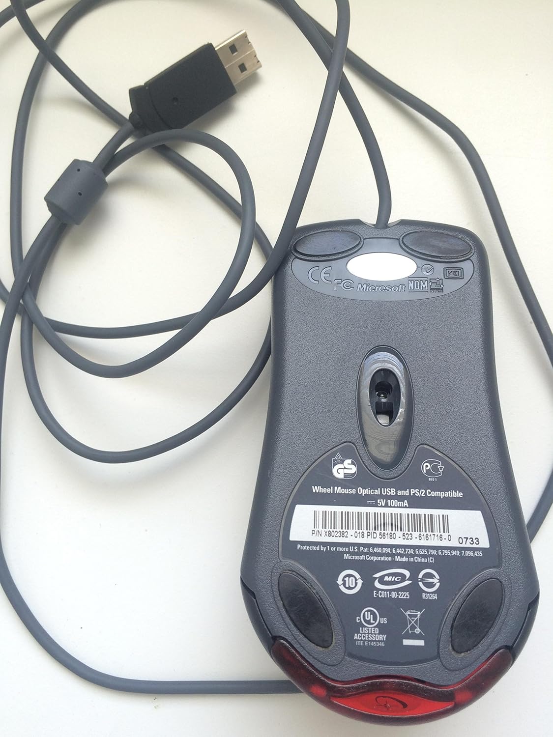 Microsoft Wheel Optical Mouse, bottom view showing optical sensor and product labels.