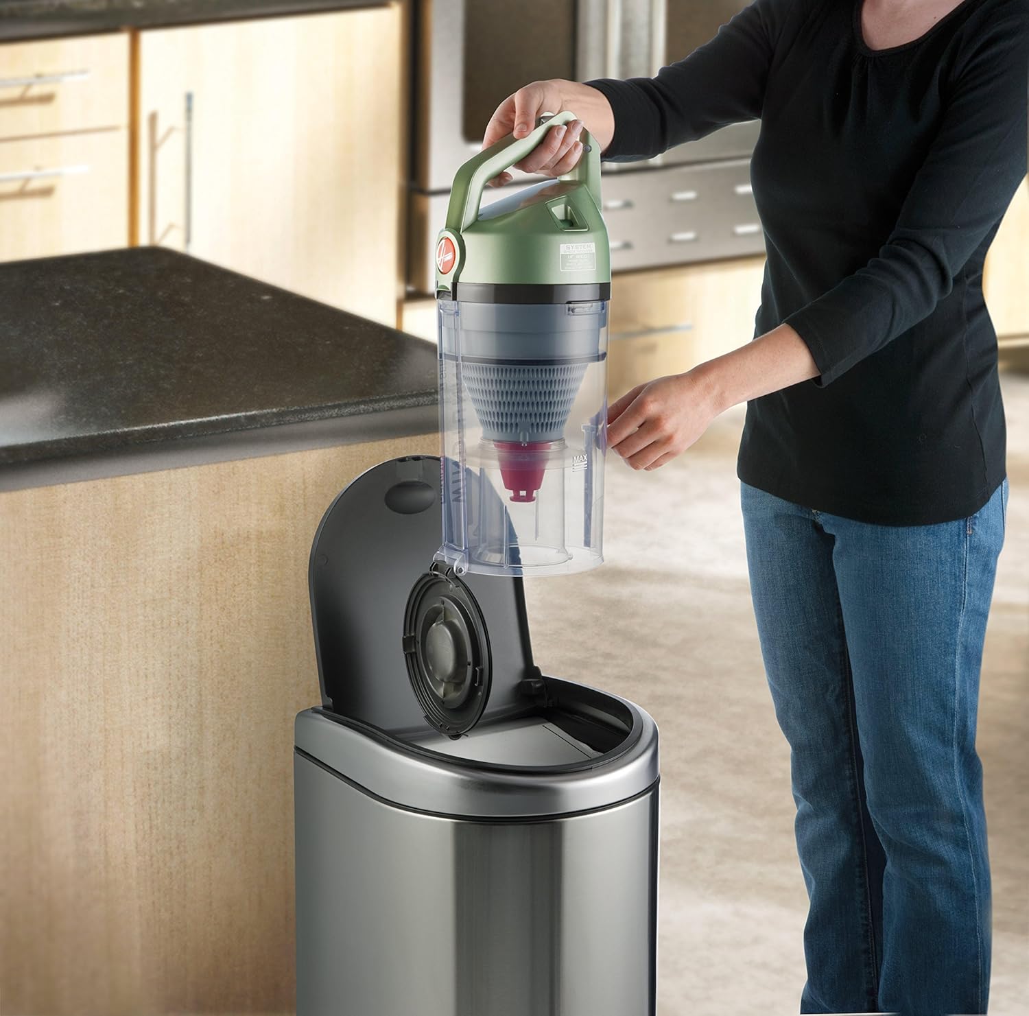 Woman emptying dirt cup of Hoover UH70120 vacuum into trash can