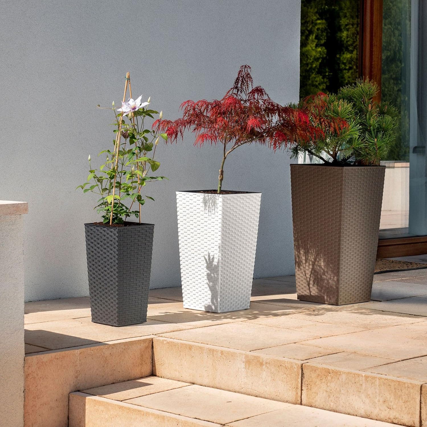Three KADAX flower pots of different colors and sizes on an outdoor patio