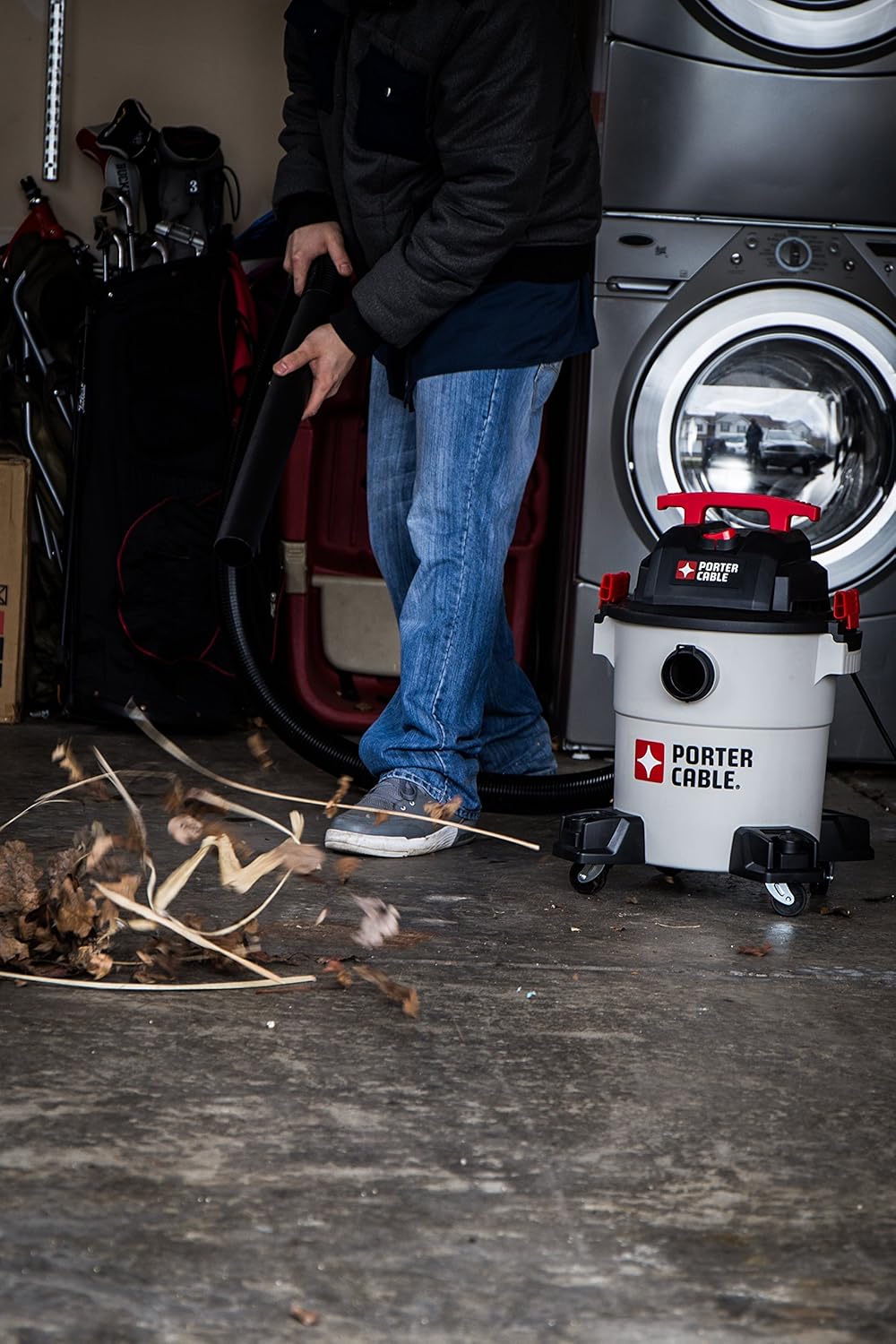 Person cleaning the wet/dry vacuum in a workshop setting