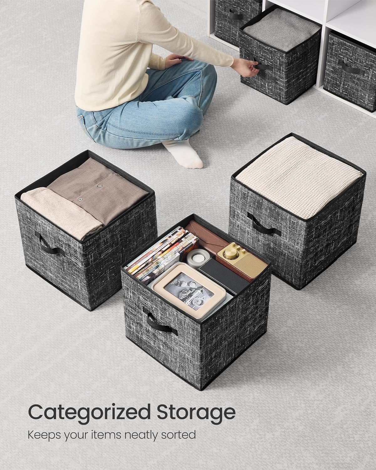An overhead view of three storage cubes, one filled with folded clothes, another with books and small items, demonstrating categorized storage.
