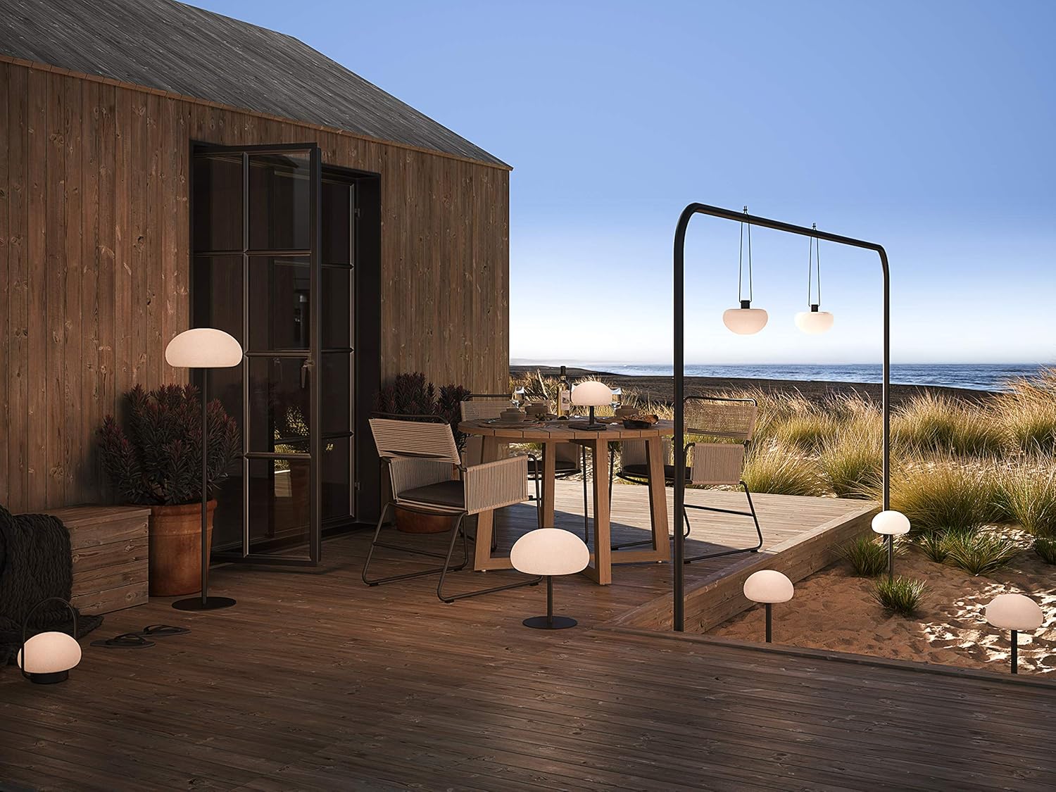 Multiple Nordlux SPONGE TO GO lamps placed in an outdoor setting on a wooden deck and sandy area, demonstrating their use in a garden or patio.