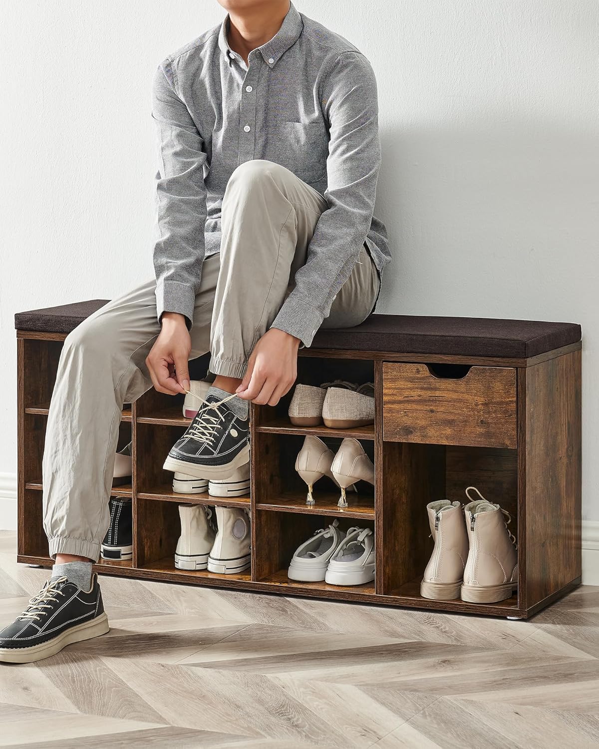 A person sitting on the VASAGLE Shoe Bench, tying their shoe.
