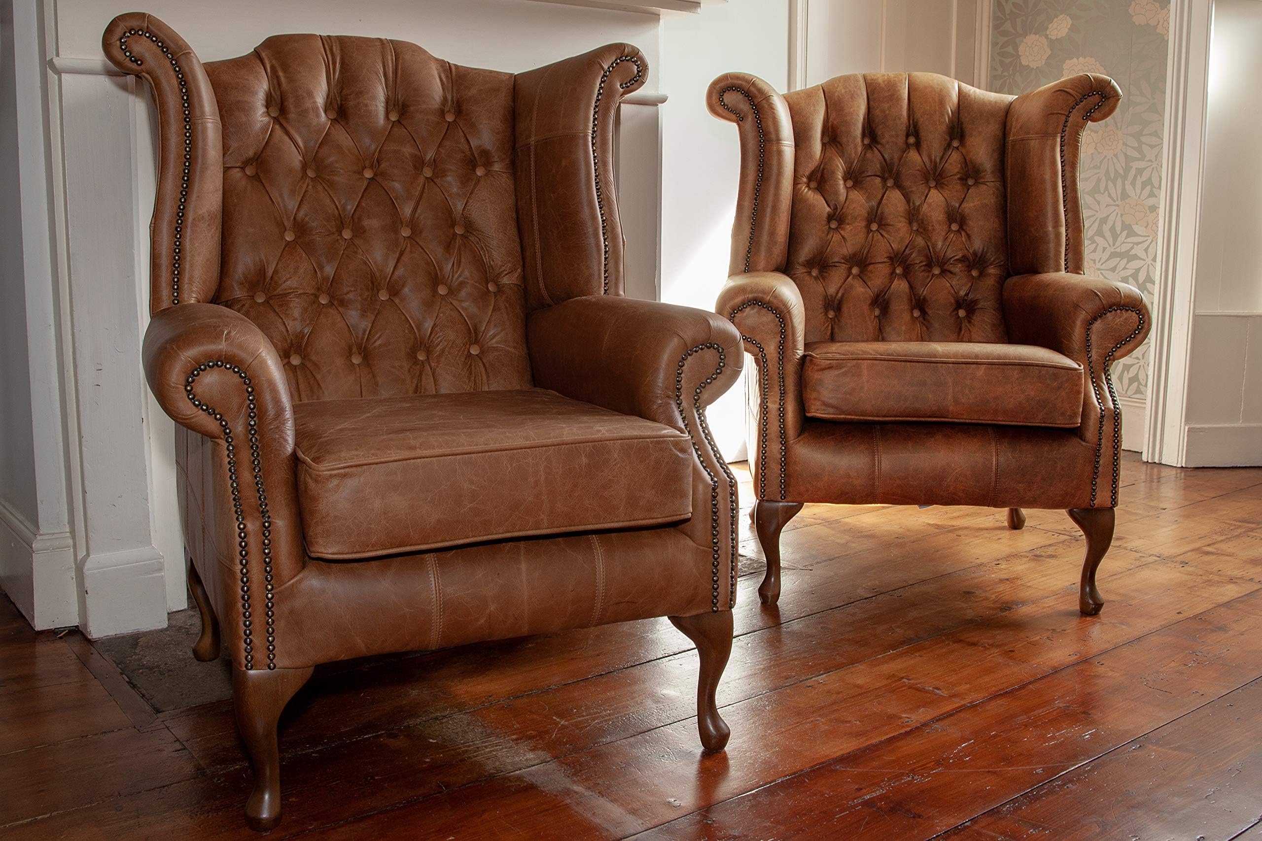 A pair of Chesterfield Queen Anne high back wing chair presented in vintage tan leather with matching foot stool