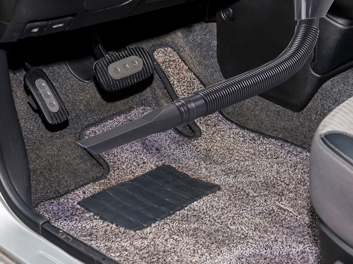 Cleaning car floor with hose and crevice tool
