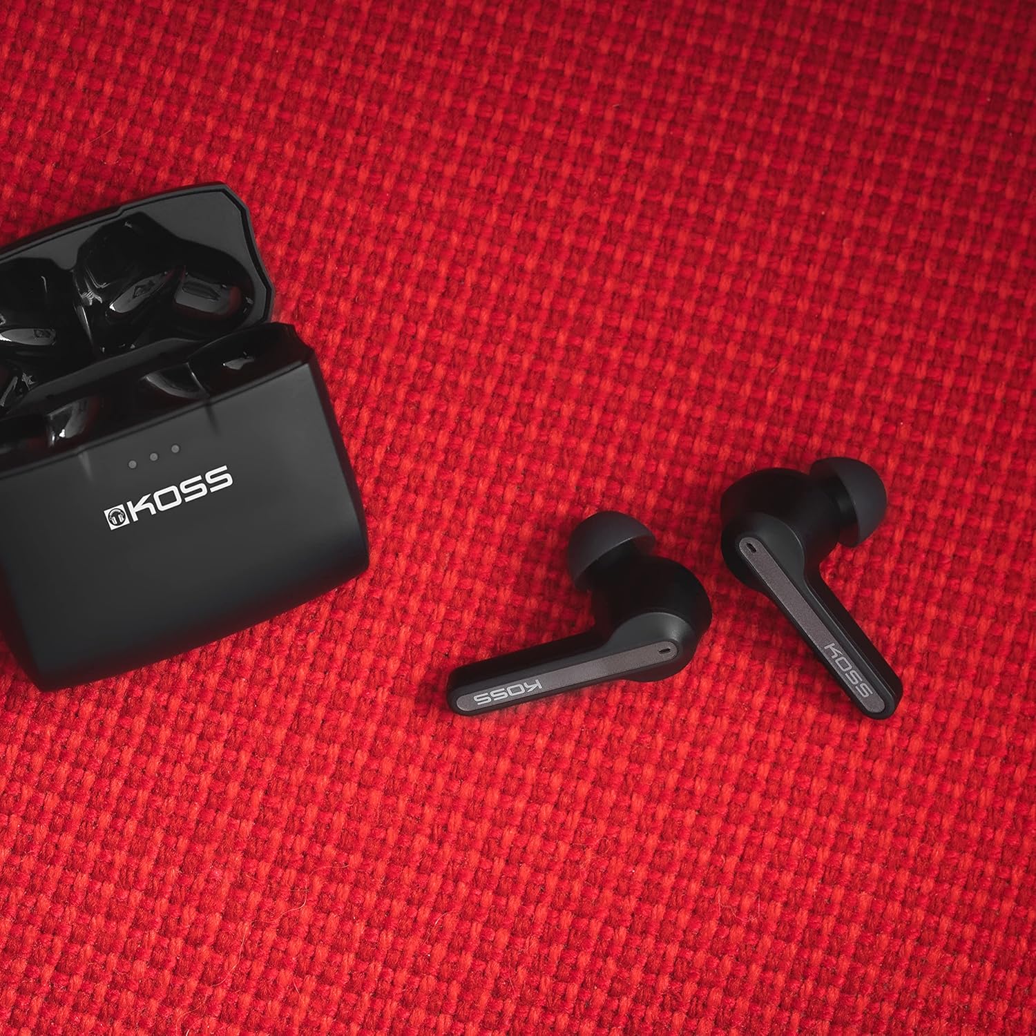 KOSS TWS150i Earbuds and case on red textured surface