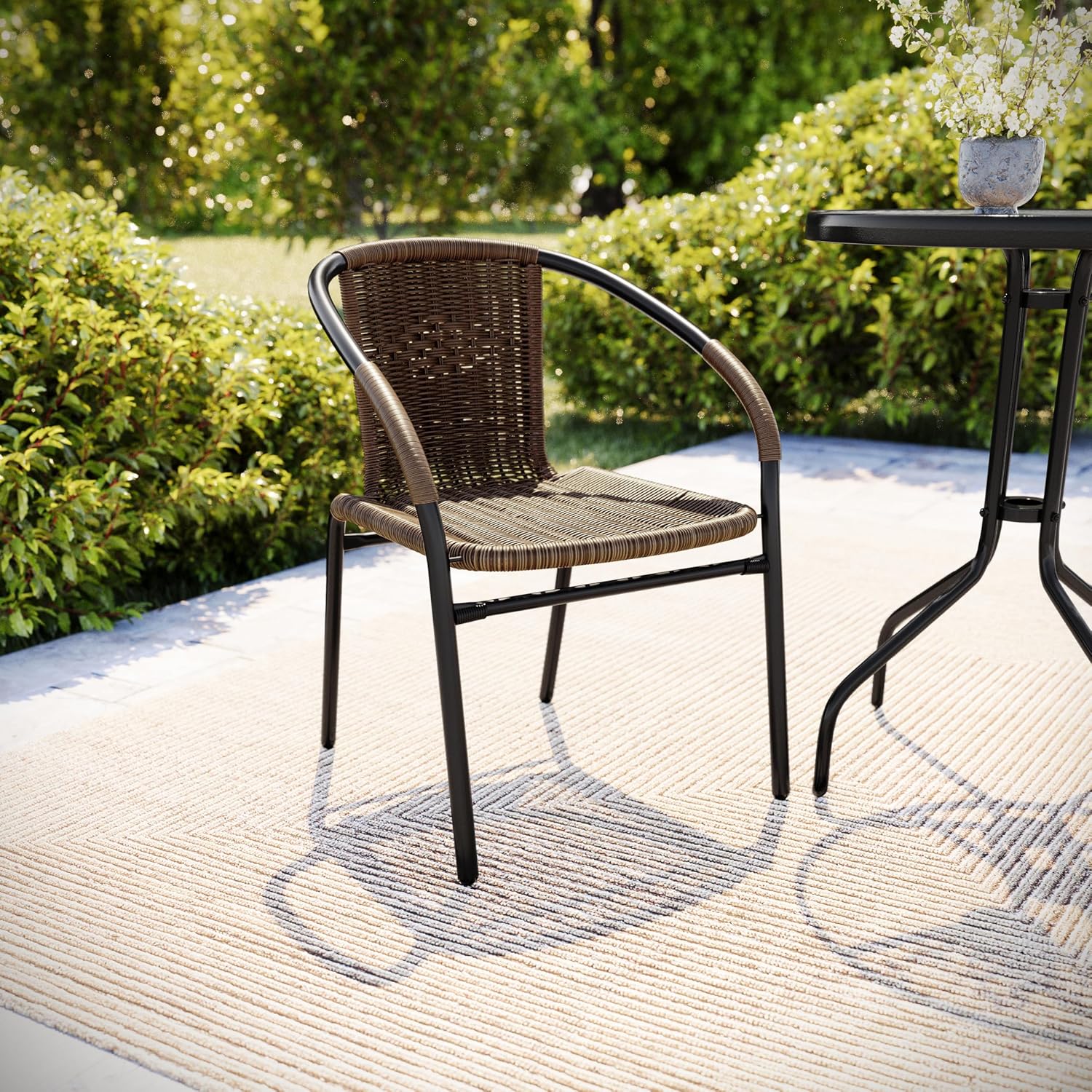 Flash Furniture Lila Rattan chair in an outdoor garden setting.