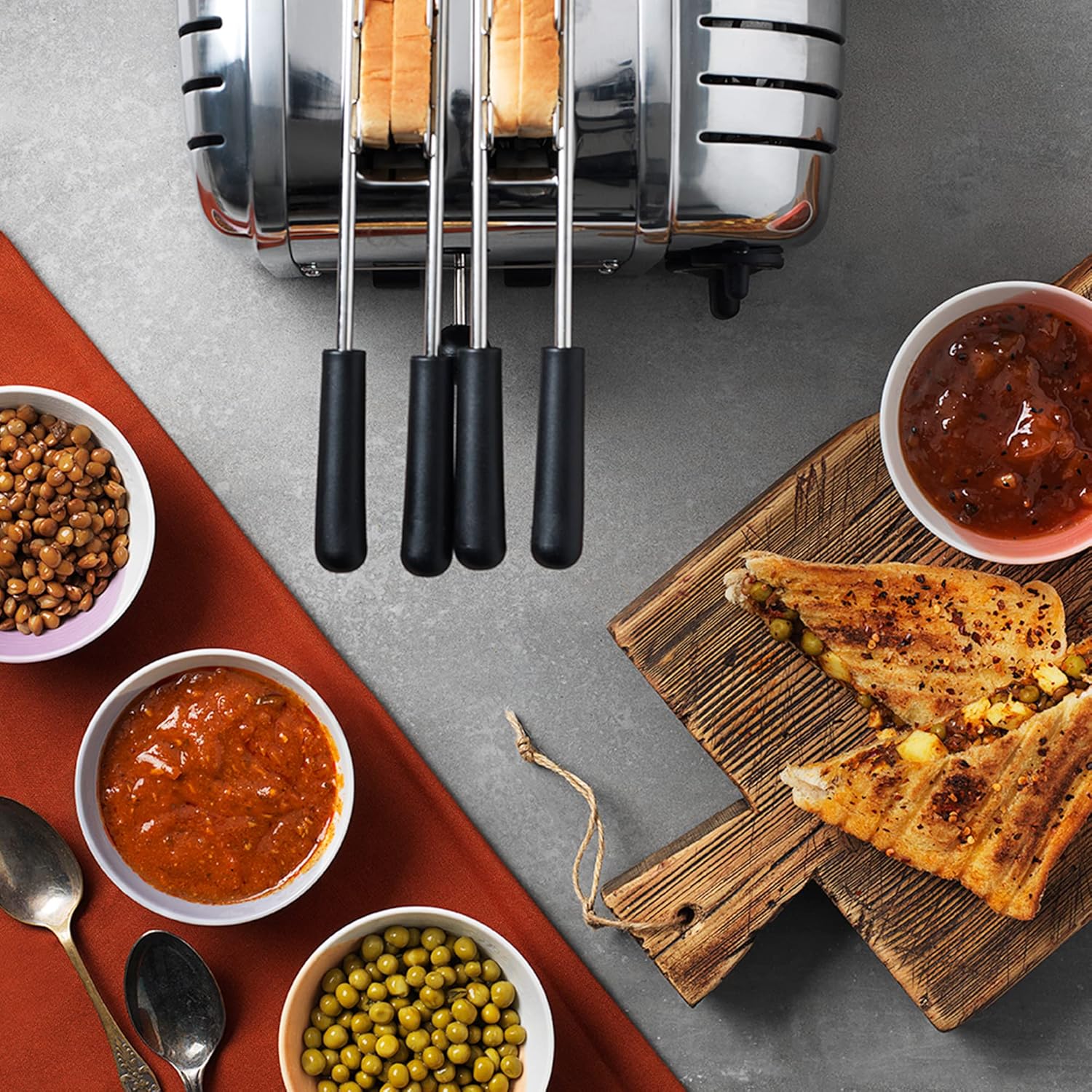 Top-down view of a Dualit 4-slice toaster with multiple sandwich cages inserted, each containing a sandwich filling.