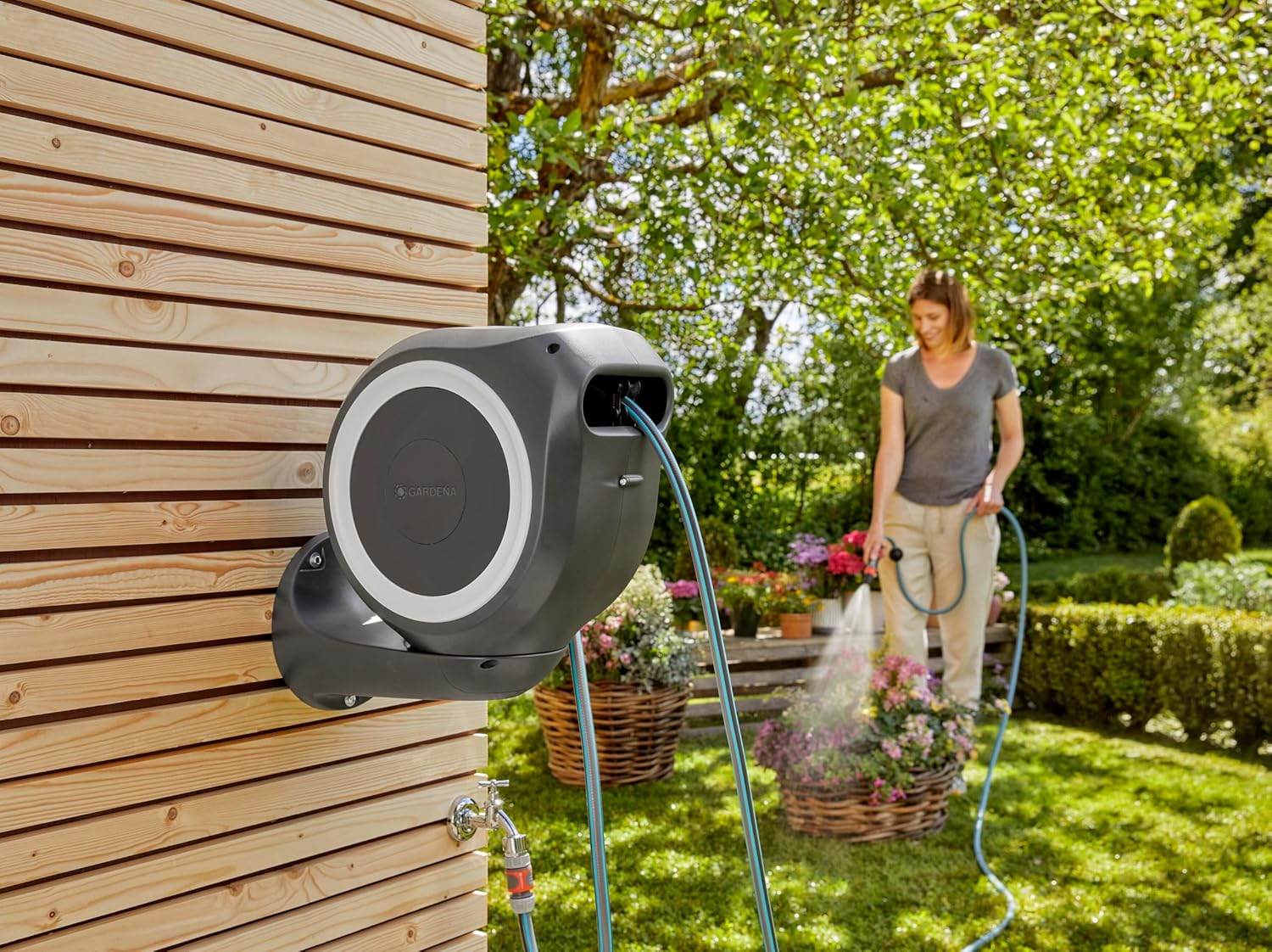 User watering plants with the Gardena Rollup S Wall Hose Box