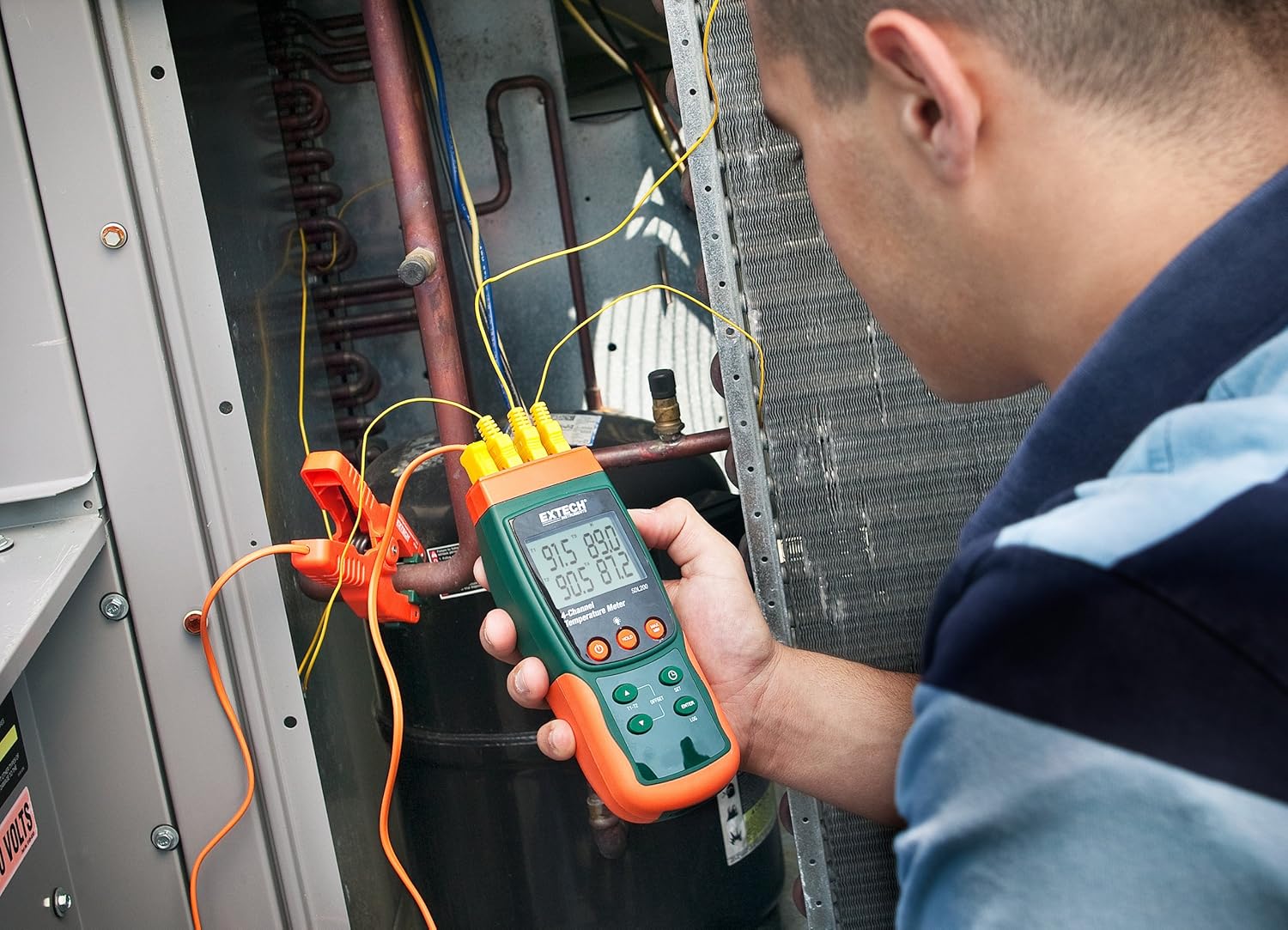Technician using Extech SDL200 to measure temperatures on an HVAC unit