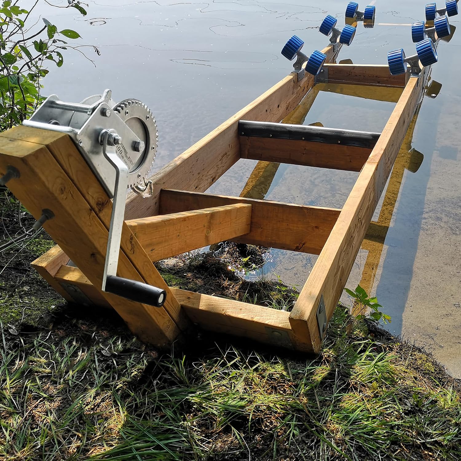 Assembled wooden boat ramp extending into the water from a grassy shoreline, ready for use.
