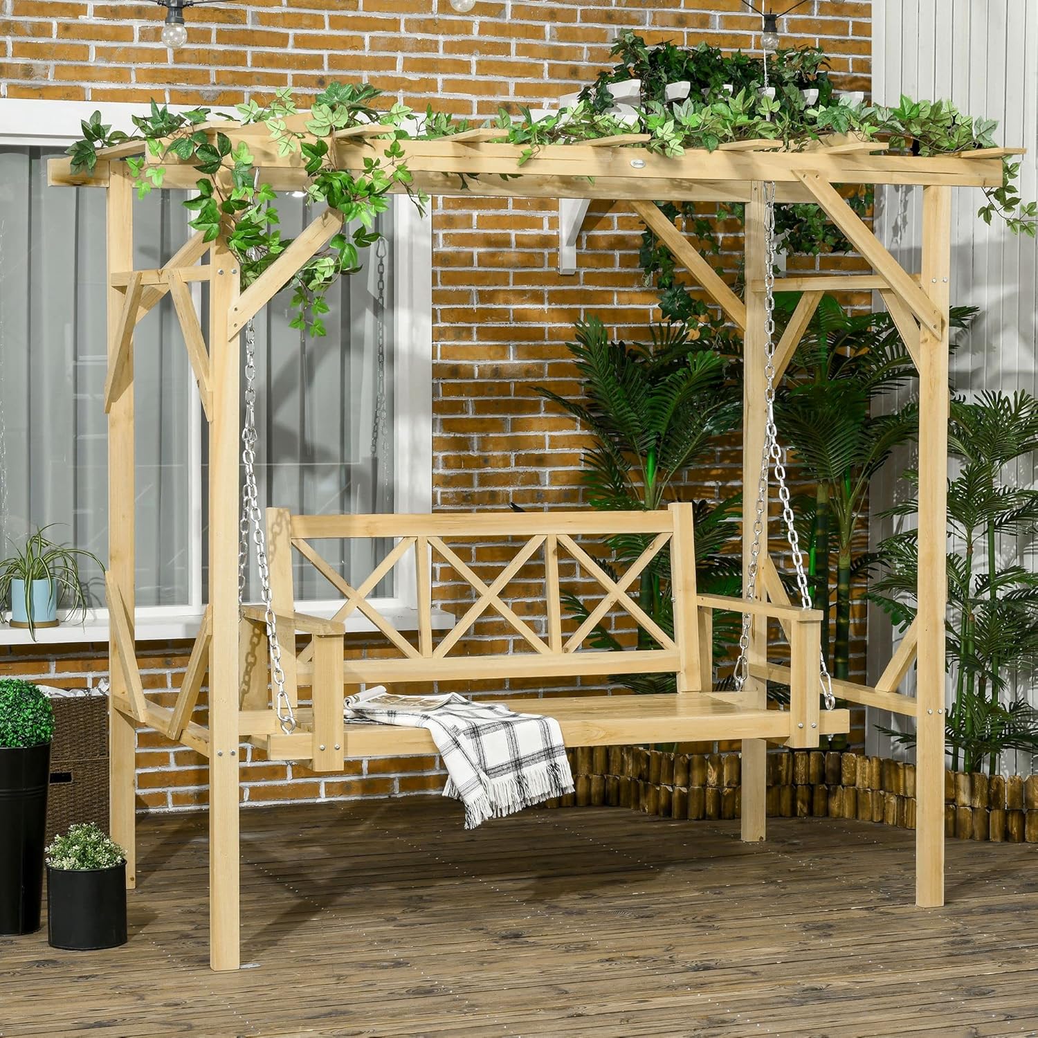 Fully assembled Outsunny 2-seater wooden swing chair with pergola, adorned with climbing plants, set on a wooden deck.