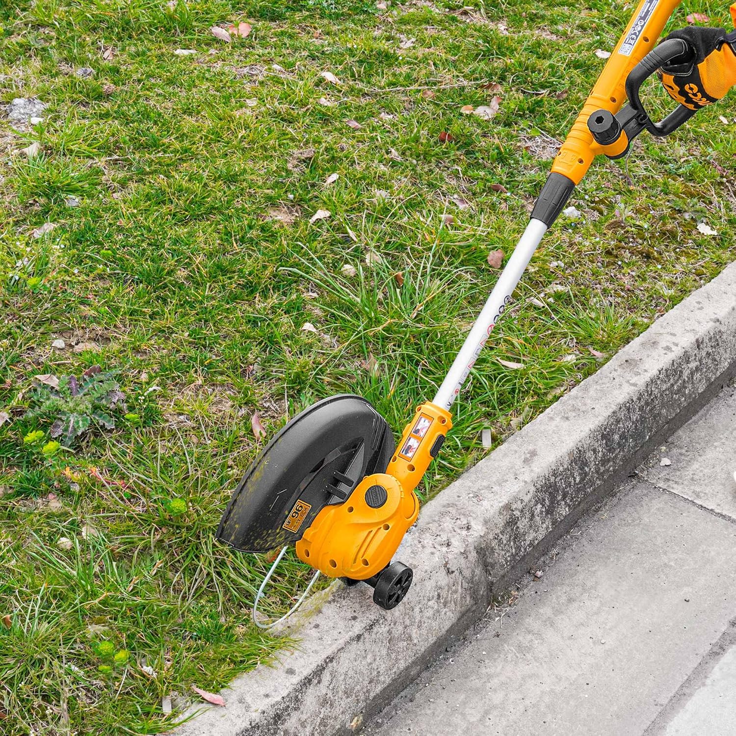 INGCO 20V Cordless Grass Trimmer used for edging along a concrete path.