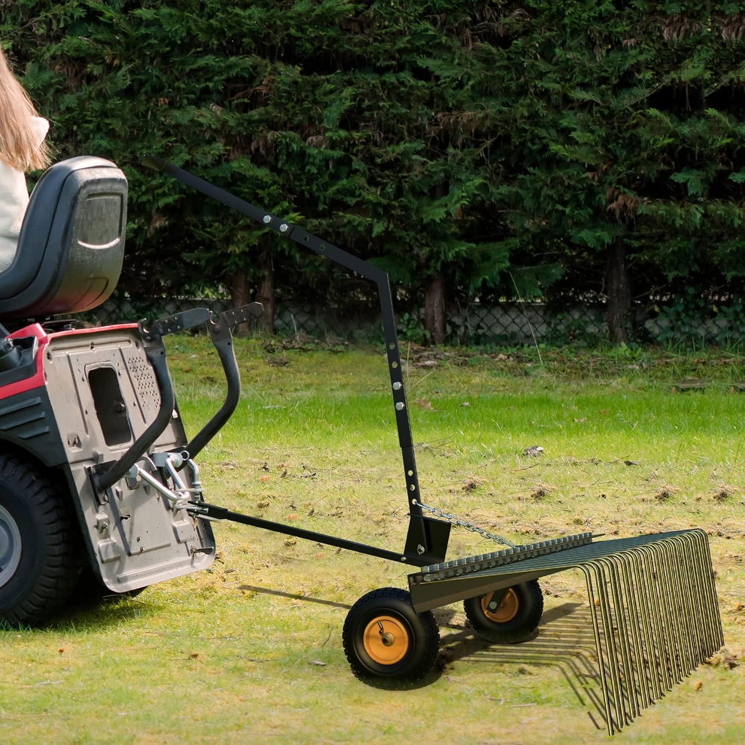 Garvee 60-inch dethatcher being towed by a riding lawn mower across a green lawn.
