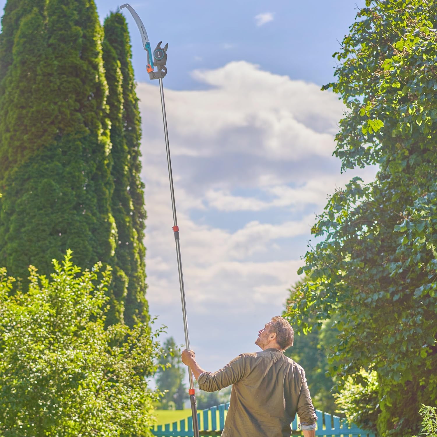 Man using telescopic pruner to cut high branch