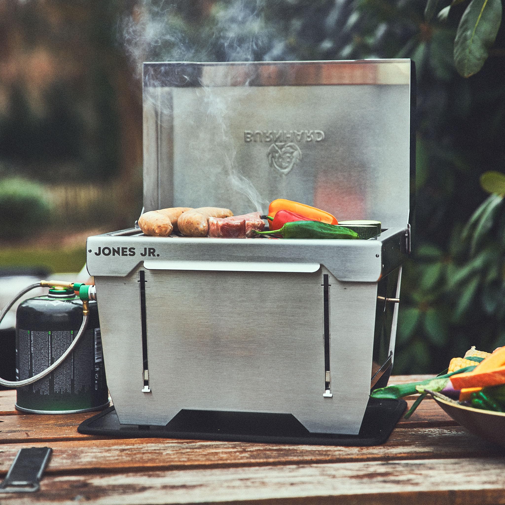 Griglia da campeggio 1-bruciatore BURNHARD® 3,2 kW, 500°C acciaio inox, sistema FitnFire™, ultracompatto, borsa da trasporto, tappetino per griglia – JONES Jr.