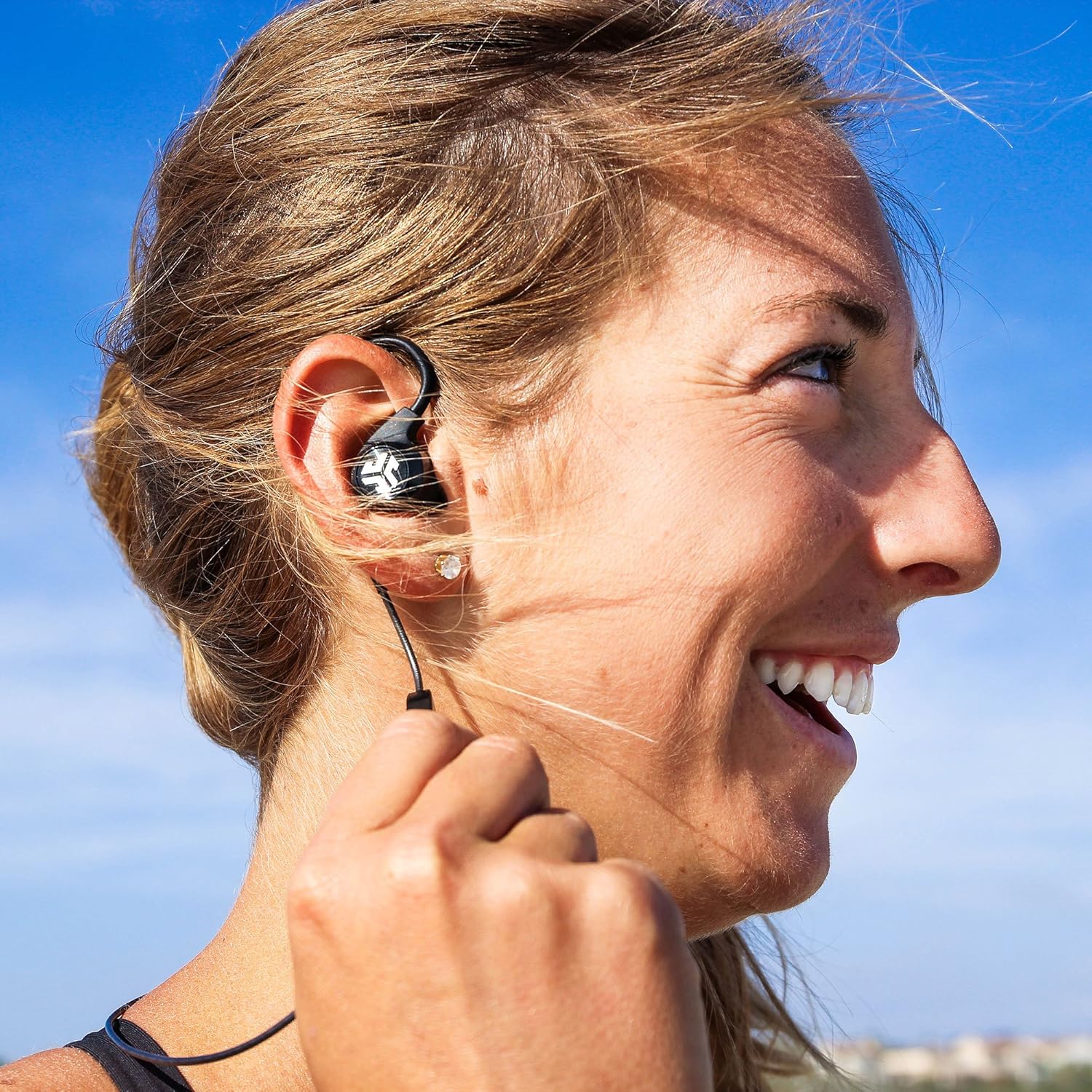 Close-up of a JLab Epic 2 earbud securely fitted into a person's ear, demonstrating the over-ear hook design.