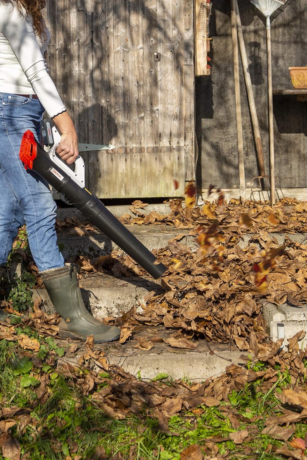 Woman using IKRA ICB 20 leaf blower to clear leaves from steps
