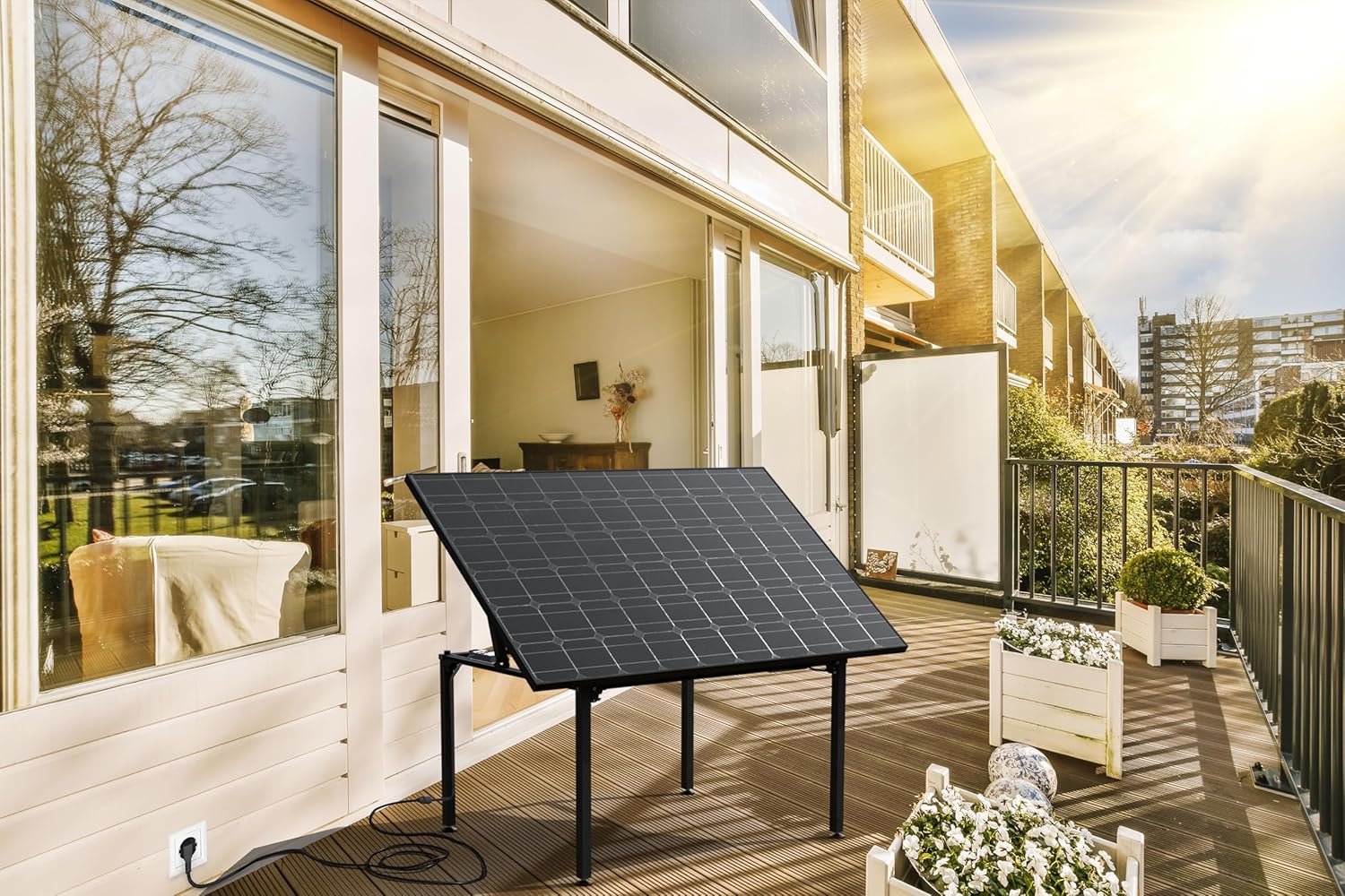 Technaxx Solar Table Power Plant TX-250 on a balcony, angled towards the sun, with a power cable plugged into an outdoor outlet.