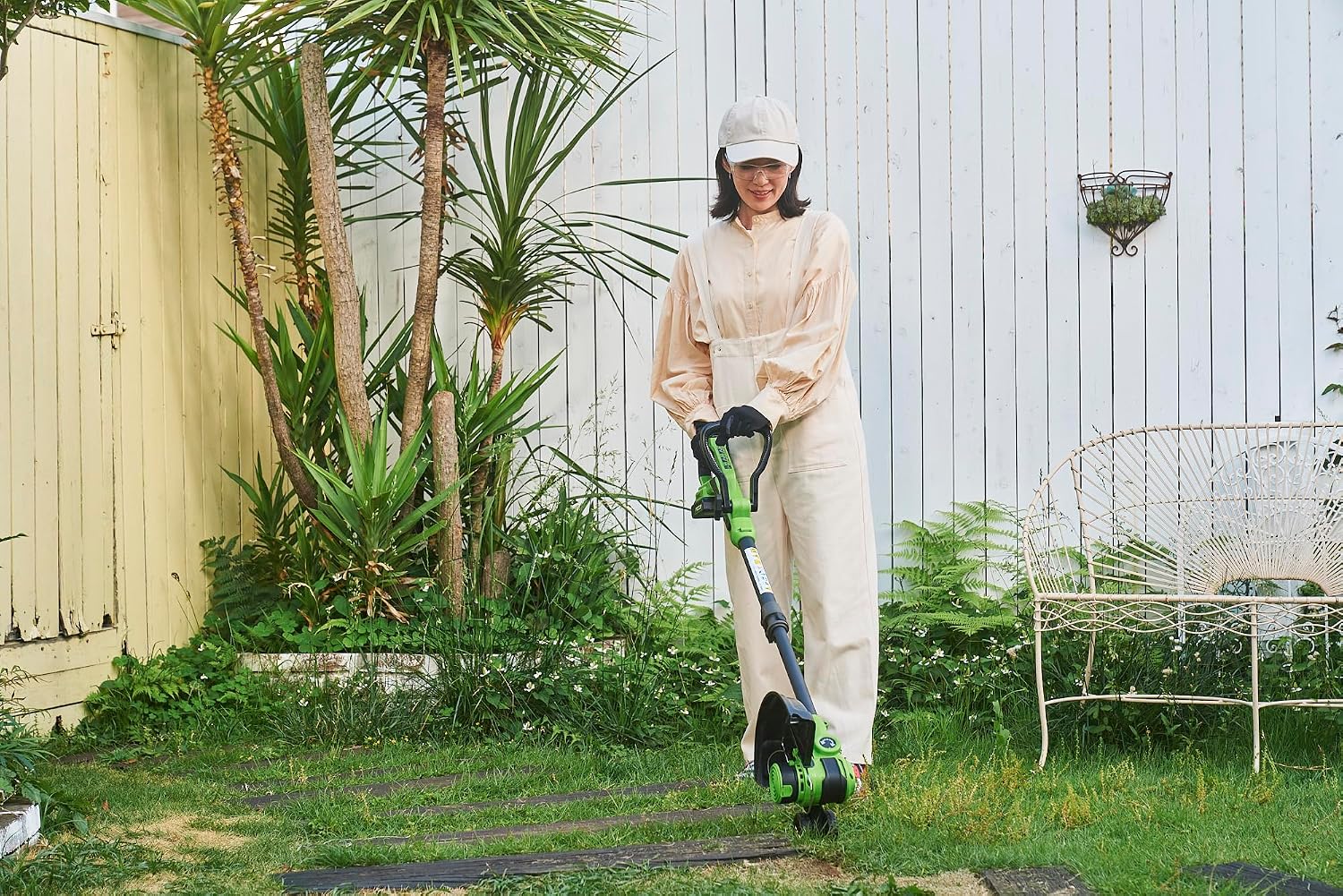 Woman operating the Greenworks 24V Grass Trimmer in a garden.