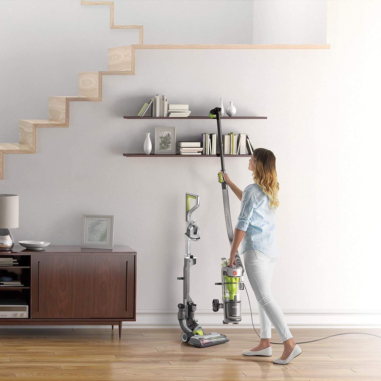 Woman using Hoover Air Lift Deluxe in lift-away mode to clean high shelves