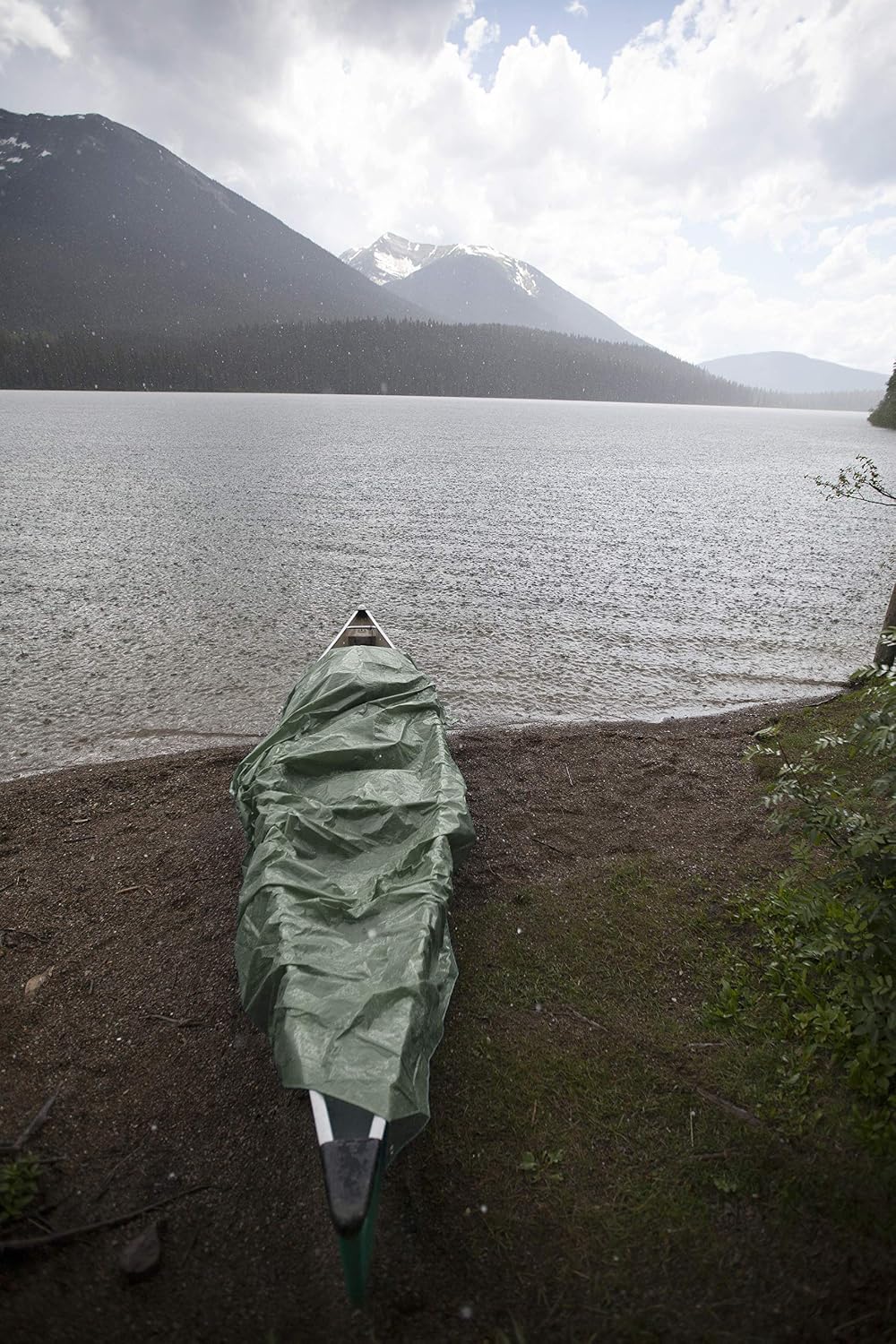 Tarp covering a canoe by a lake
