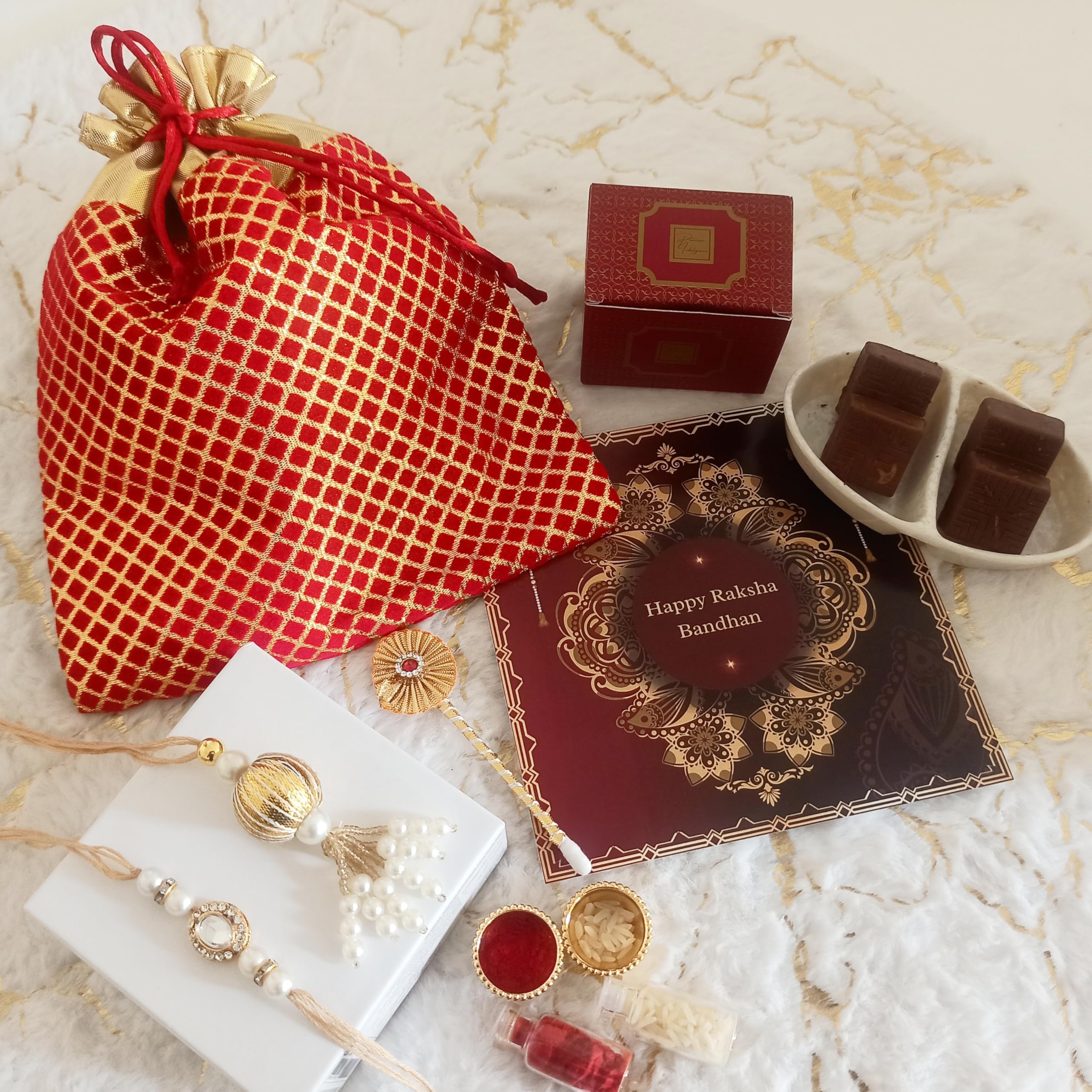 NutriSnacksbox Rakhi Gift Hamper for Brother with Elegant Red Potli| 1 Rakhi 1 Lumba| Roli Chawal | Tikka Stick | Chocolate Biscuits | Greeting Card