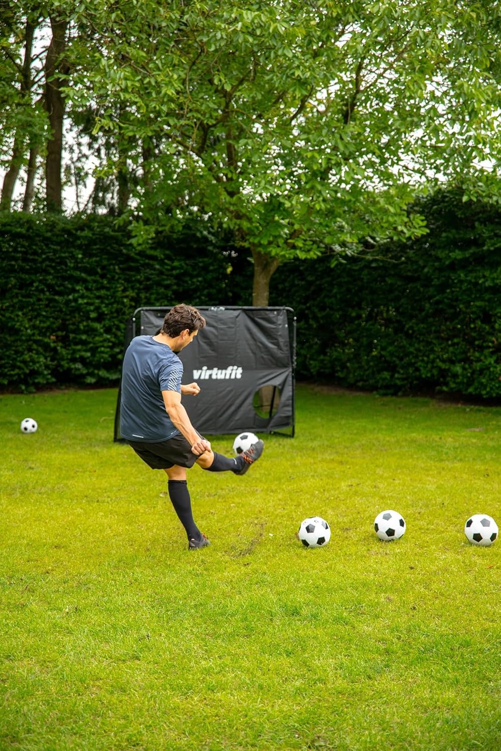 Adult male practicing shooting with the VirtuFit Football Goal Pro target sheet.