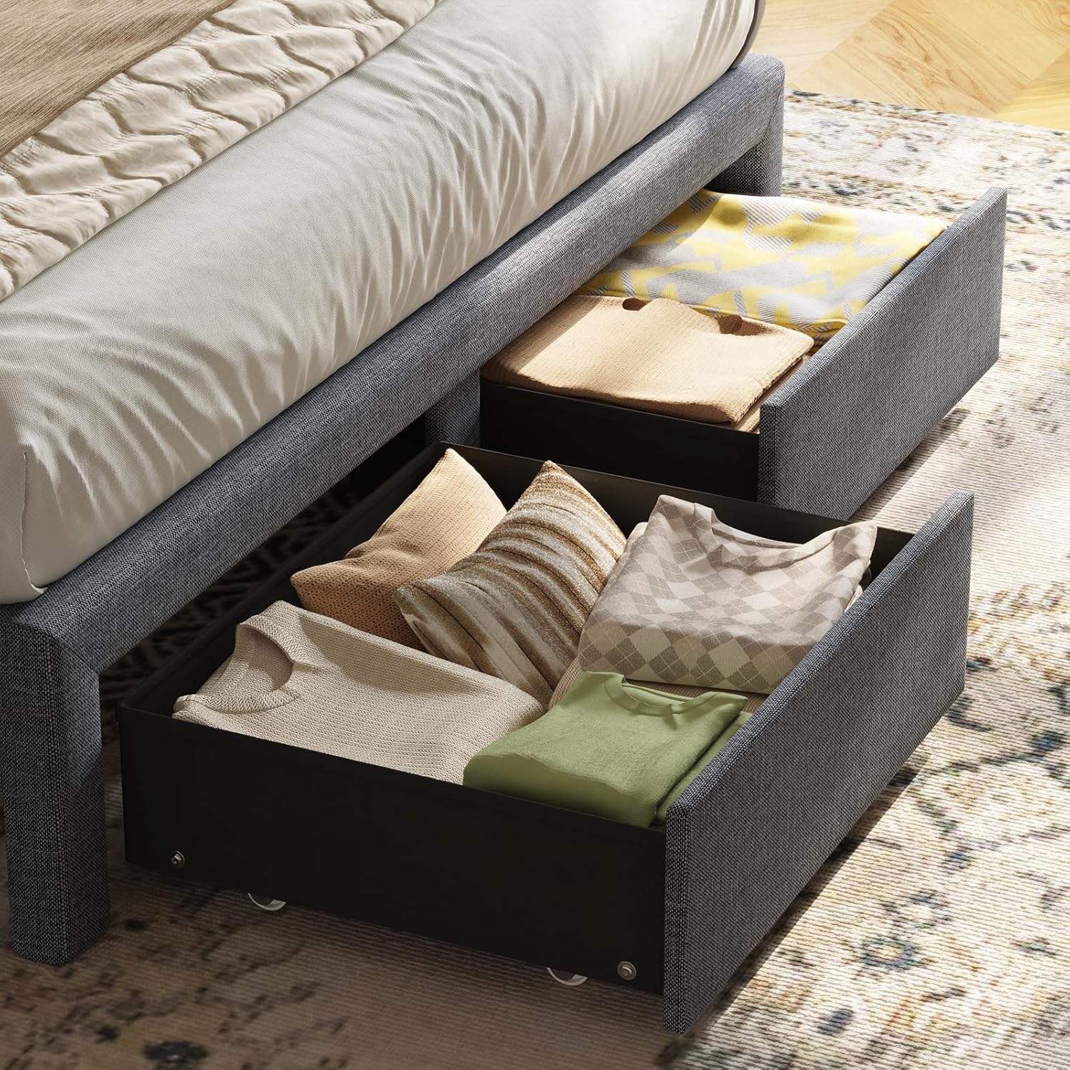 Close-up view of the two fabric storage drawers under the bed frame, filled with folded clothing and pillows.
