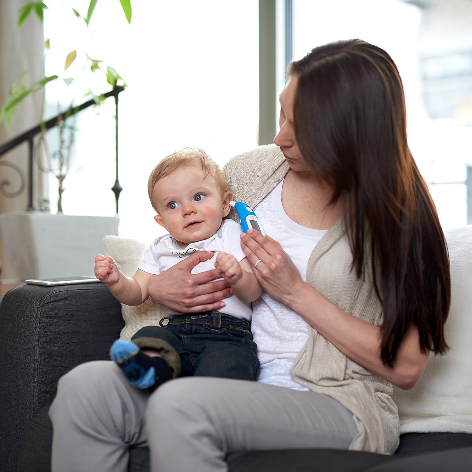 Parent taking a baby's temperature with the Kinsa Smart Ear Thermometer while holding the baby