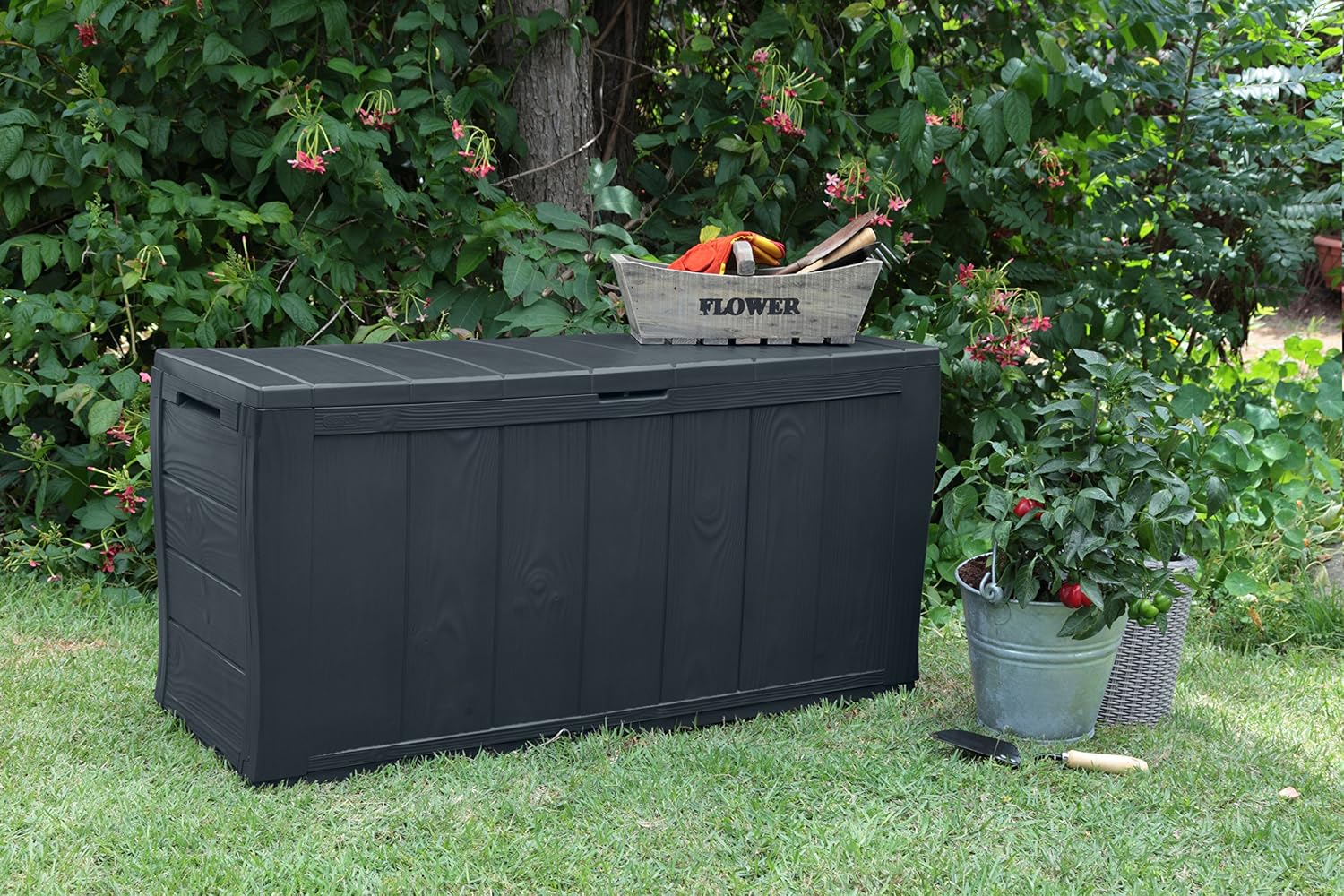 Keter Sherwood 270L Storage Box placed in a garden setting, surrounded by plants
