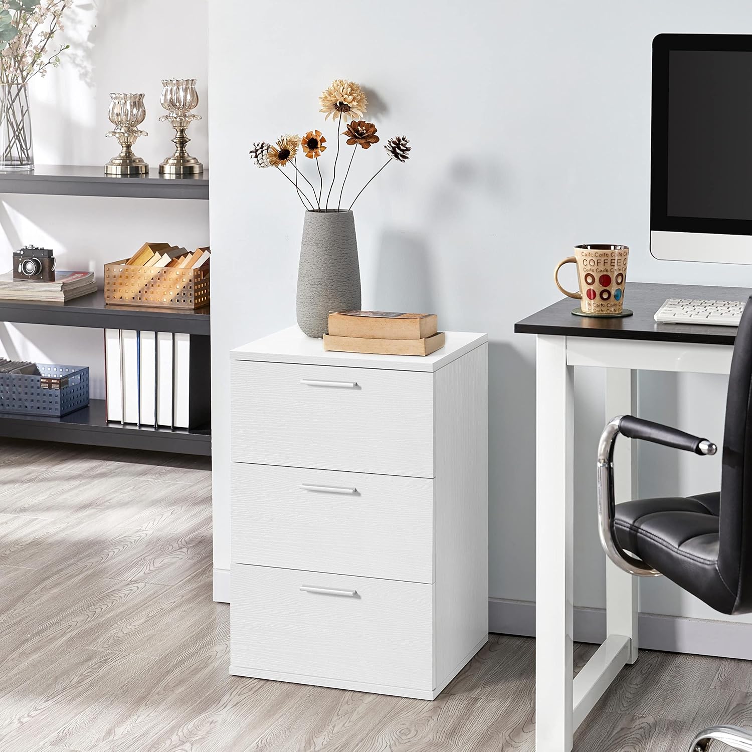 The white nightstand placed next to a desk in an office setting, holding books and a vase.