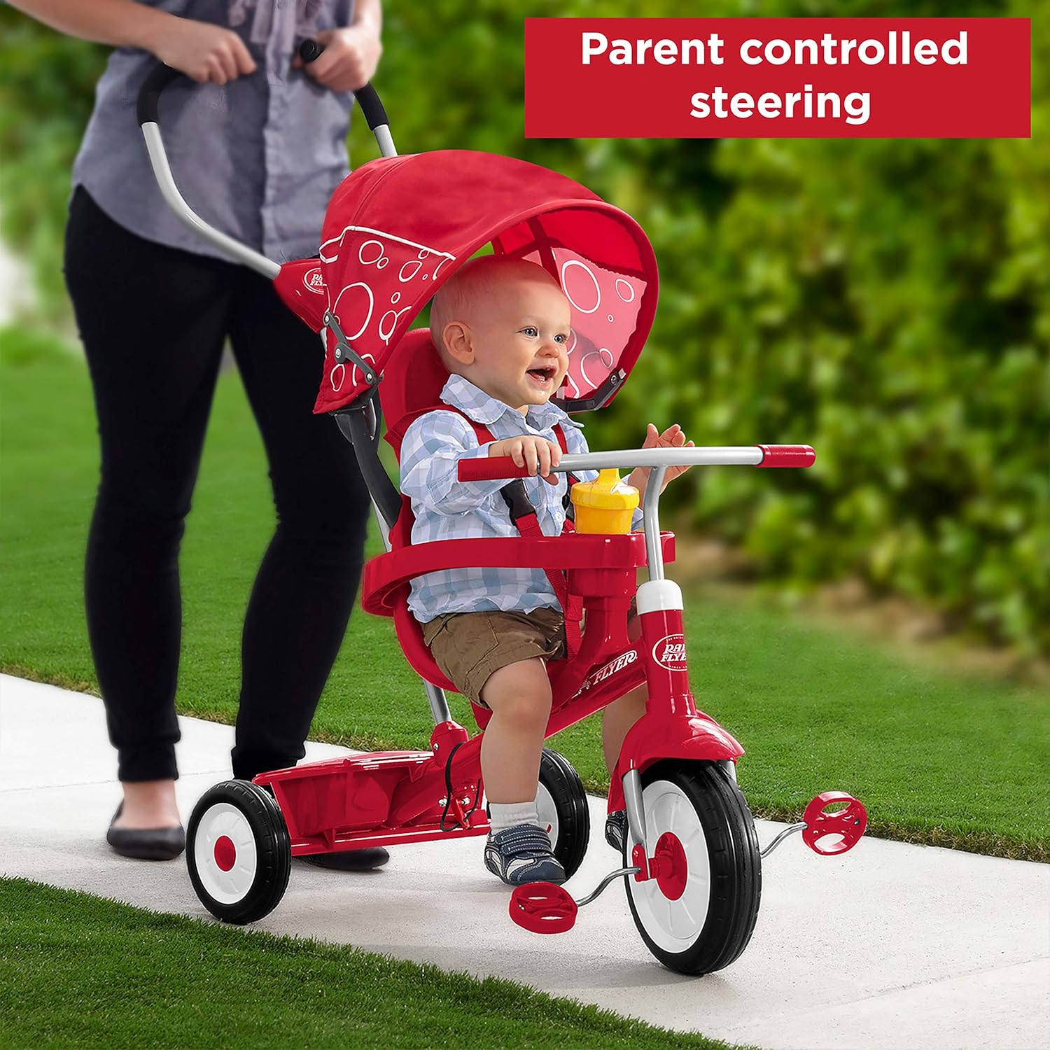 An adult pushing the trike, demonstrating parent-controlled steering.