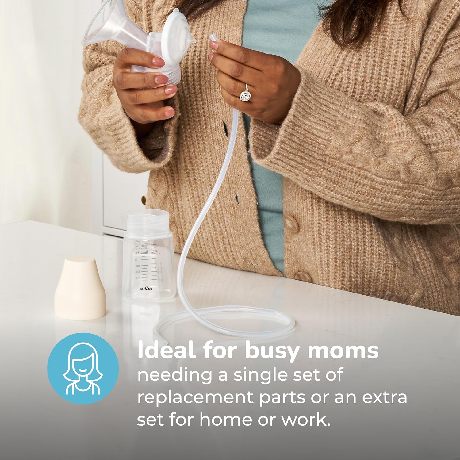 A woman demonstrating the assembly of a Spectra breast pump accessory kit, connecting the tubing to the backflow protector and flange.