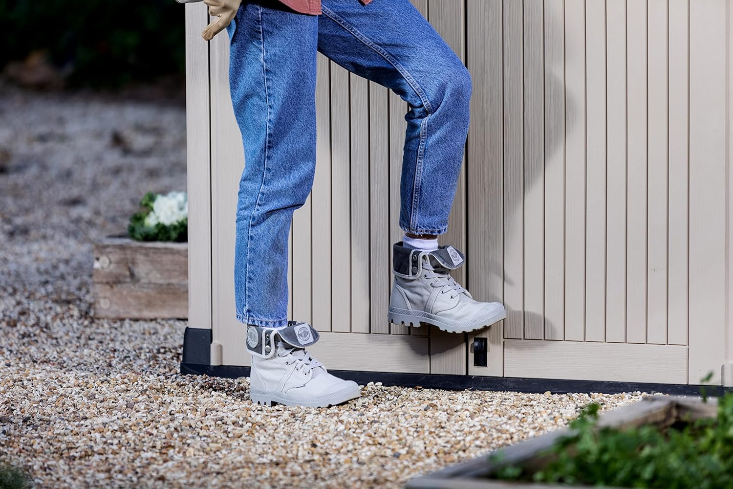 A person's foot demonstrating the foot-operated latch mechanism on the Keter Store It Out Midi storage shed.