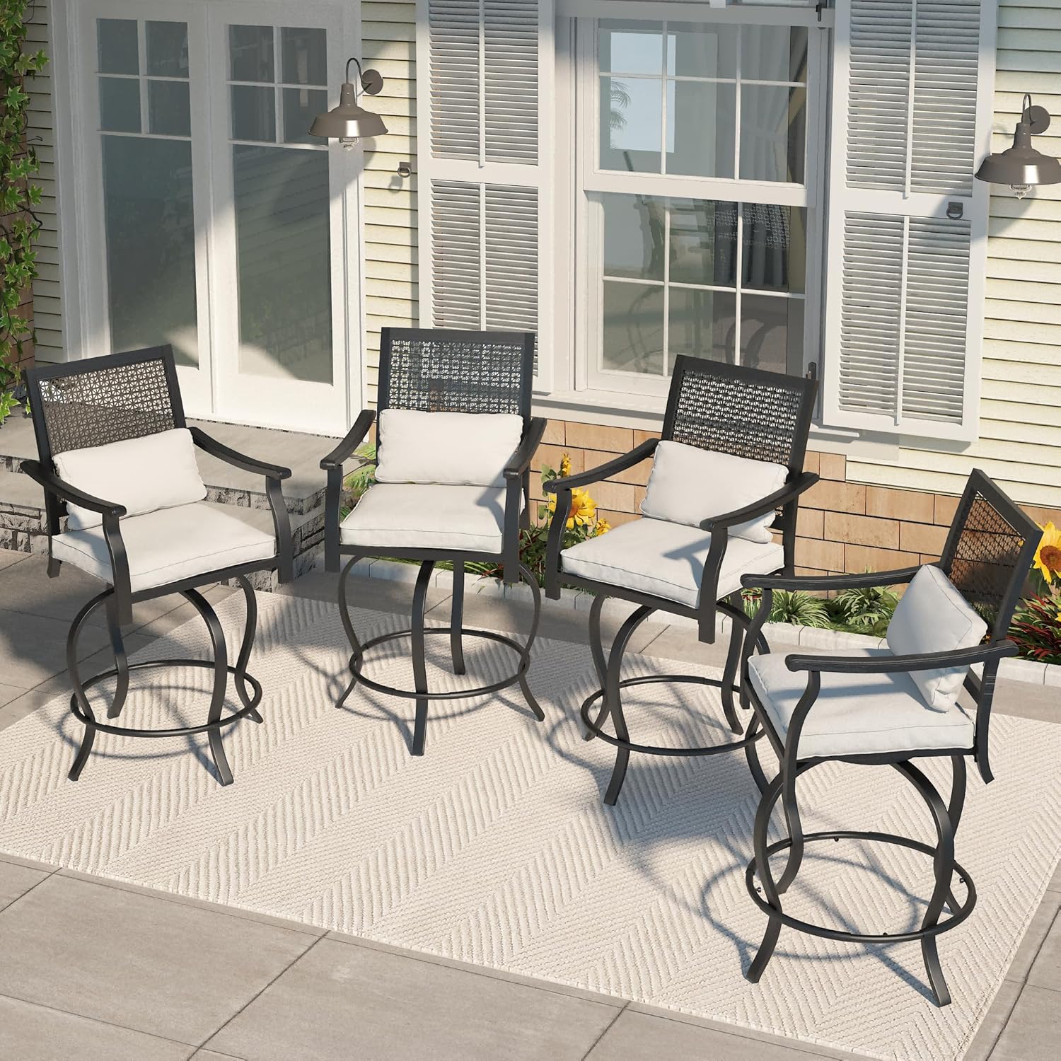 Four AECOJOY outdoor swivel bar stools with beige cushions arranged on a patio rug outside a house.