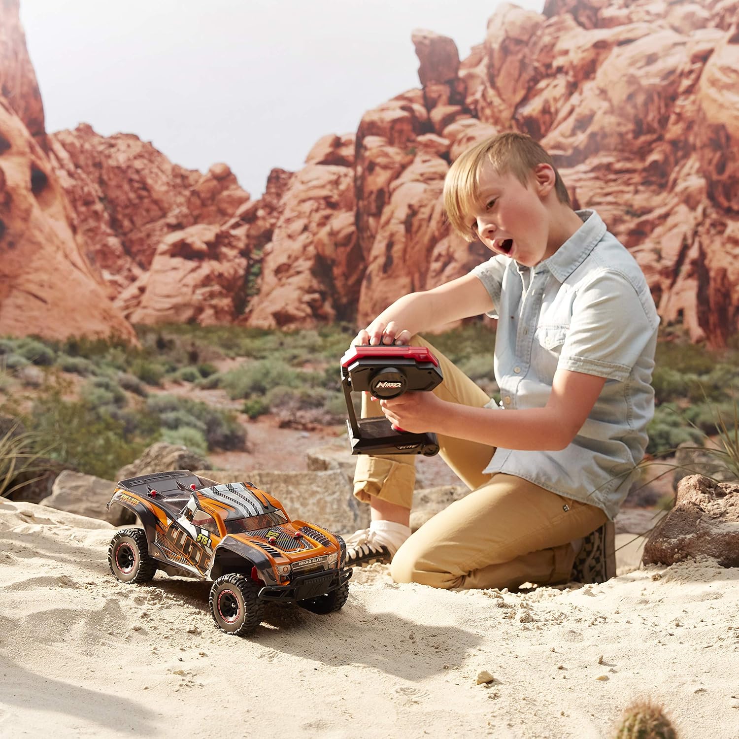 Child operating Nikko RC Elite Trucks in a desert landscape