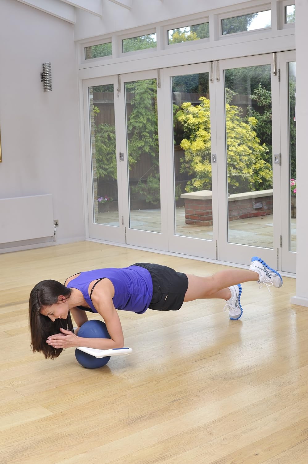A woman holding a plank position with her forearms resting on the Reebok Train Pod, engaging core muscles.