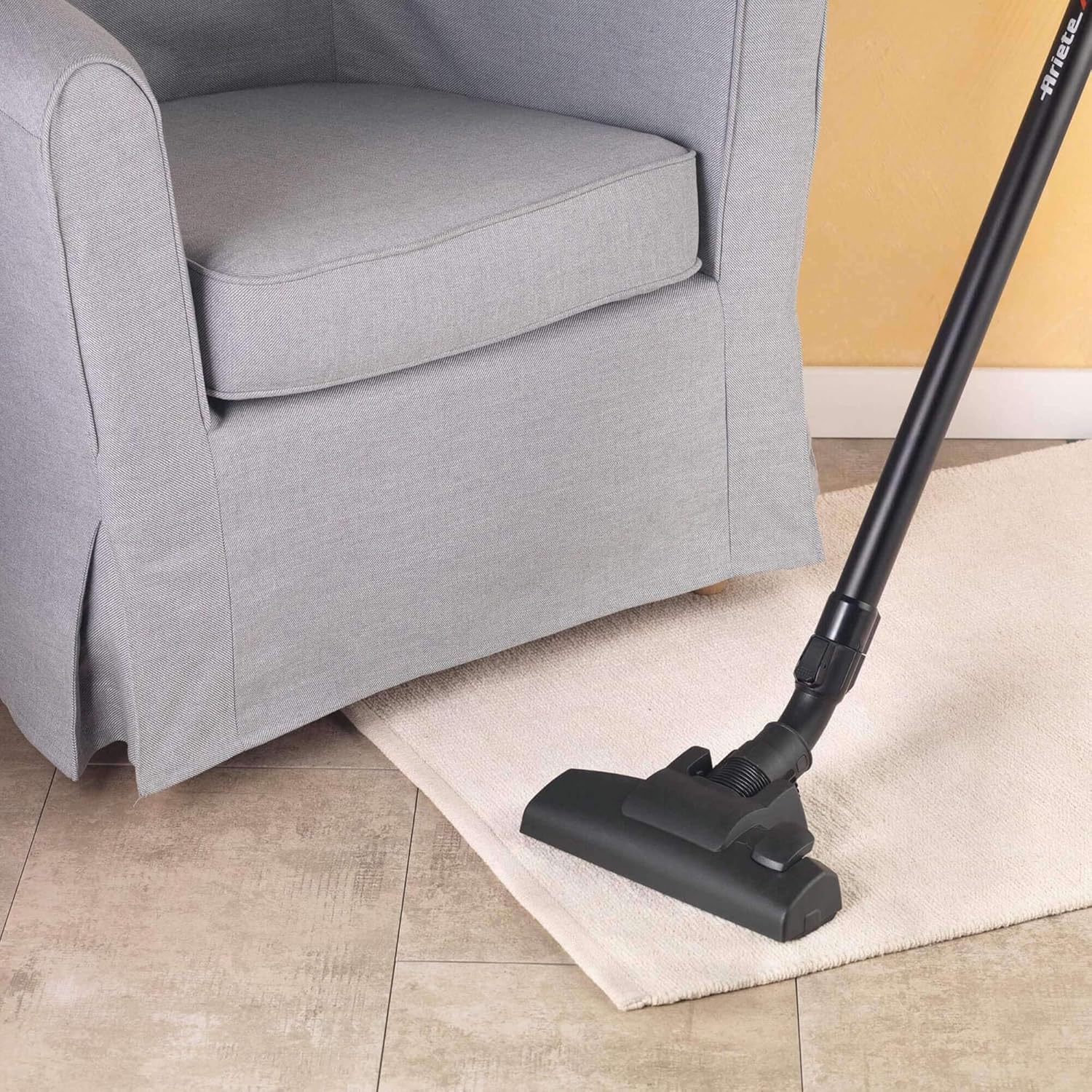 Stick vacuum cleaning a rug next to a chair
