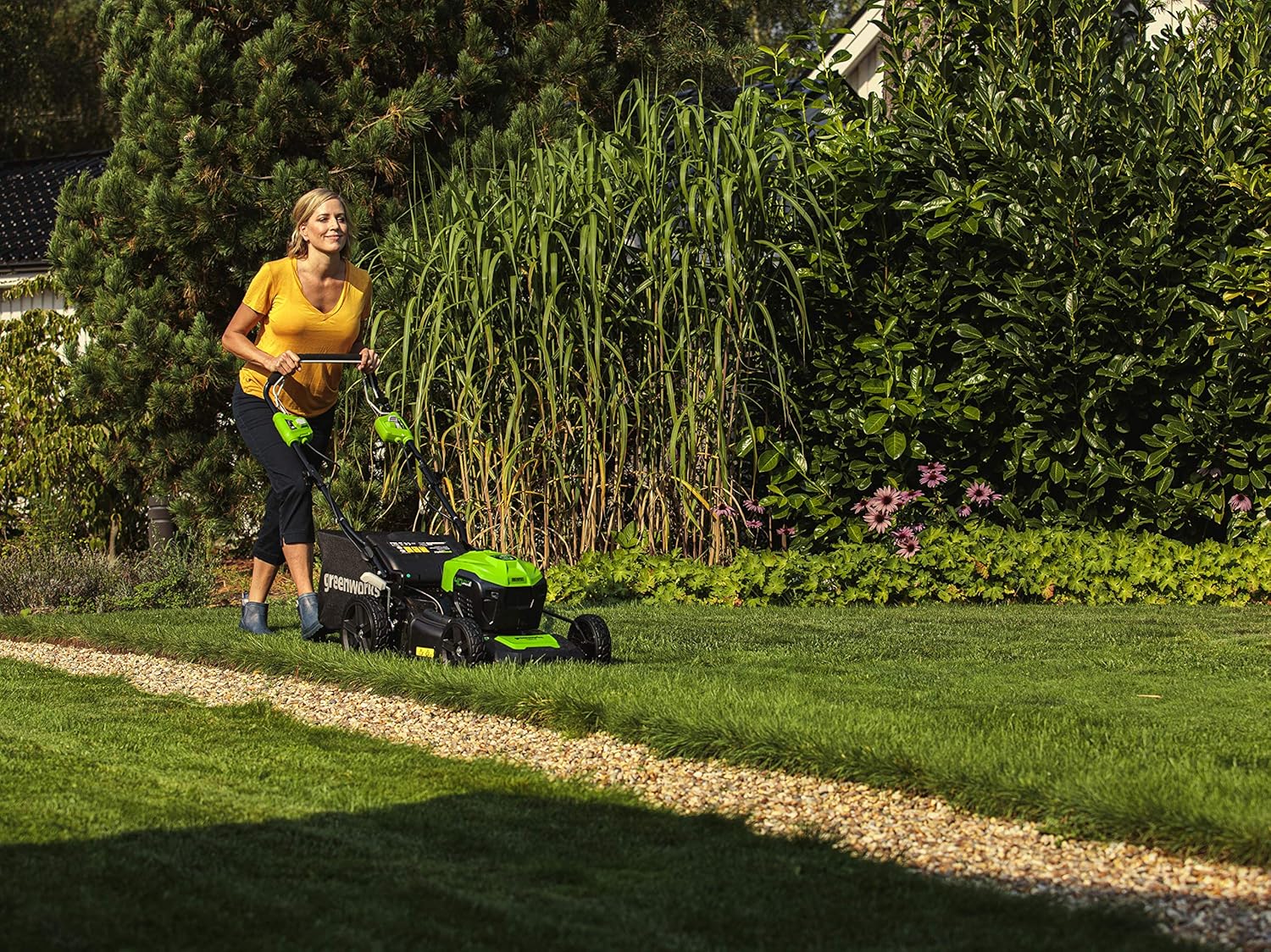 Woman operating Greenworks self-propelled lawn mower