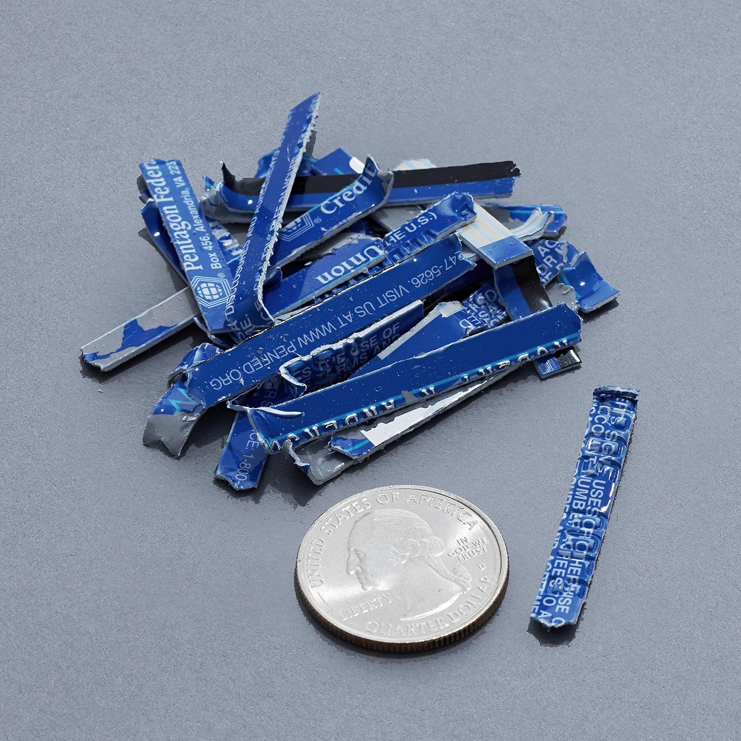 Pile of shredded credit card pieces next to a quarter for size comparison