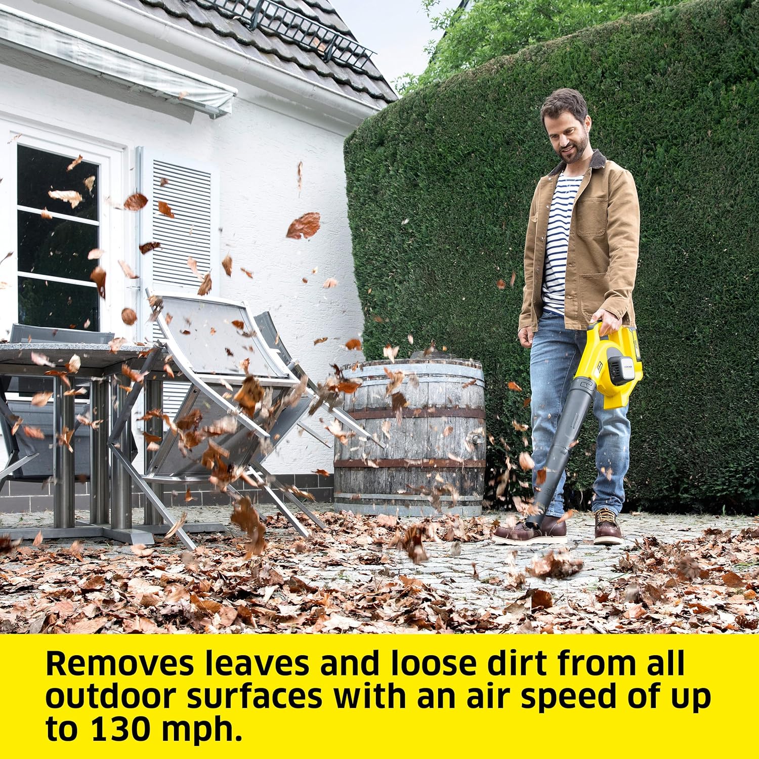 A person using the Kärcher LBL 2 Cordless Leaf Blower to clear leaves from a patio area.
