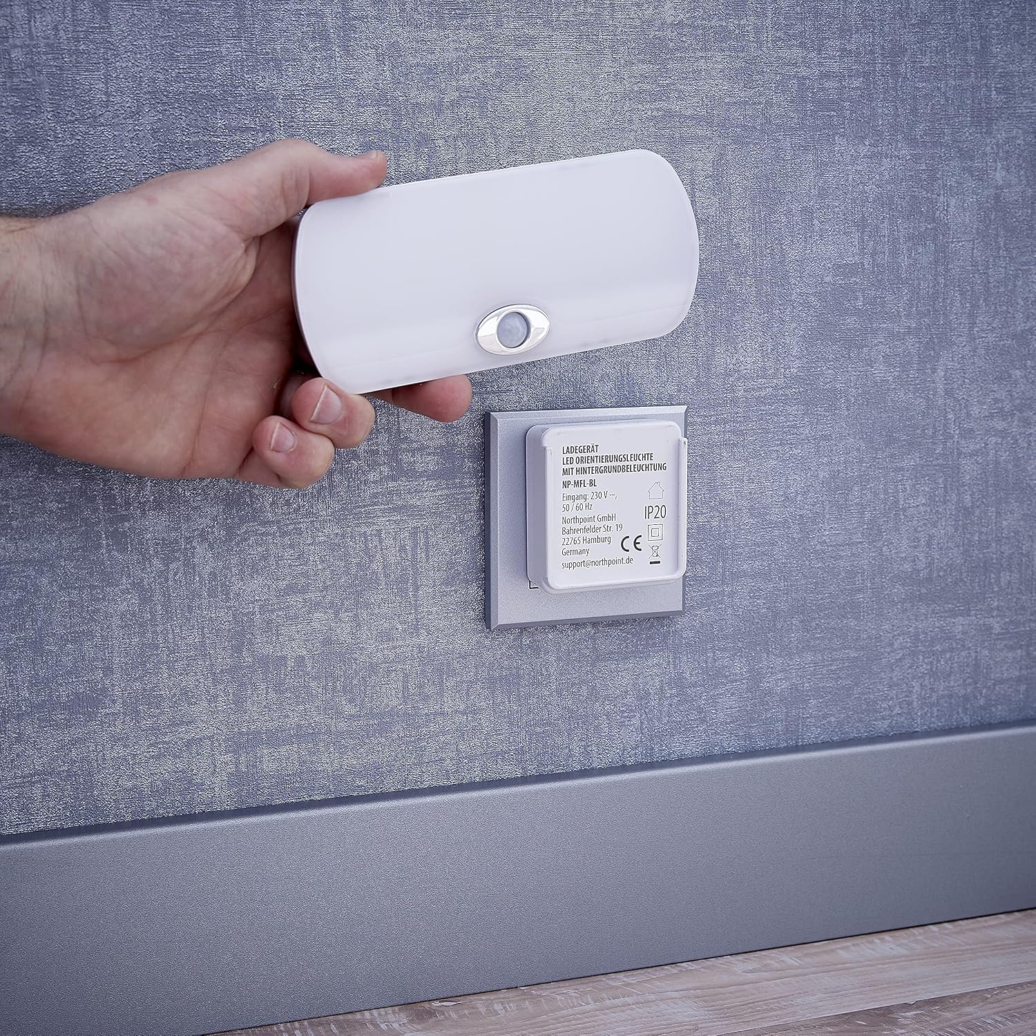 Northpoint LED Night Light being removed from its induction charging base, which is plugged into a wall socket.