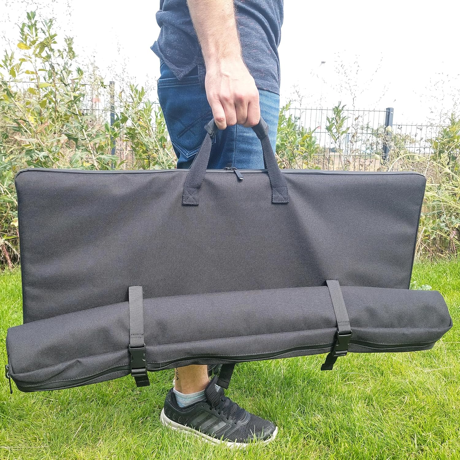 Person carrying the Technaxx TX-252 Foldable Solar Camping Table in its black carrying bag.