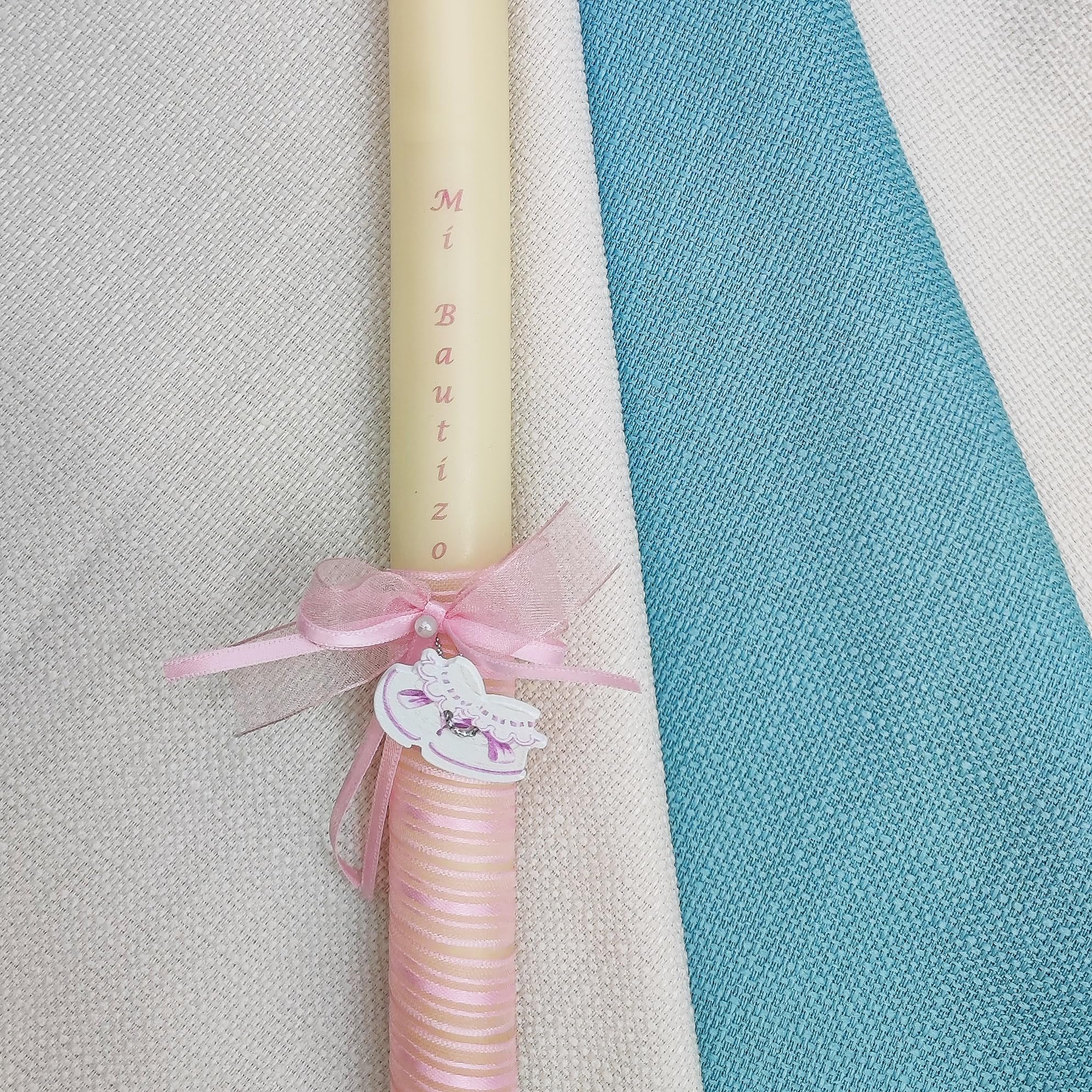Vela de bautizo 32 zapatitos de bebé (30 x 2 cm) decorada con una cinta en espiral, un lacito con dos perlas, y un adorno de zapatitos de bebé en rosa o azul. Personalización impresa en la cera